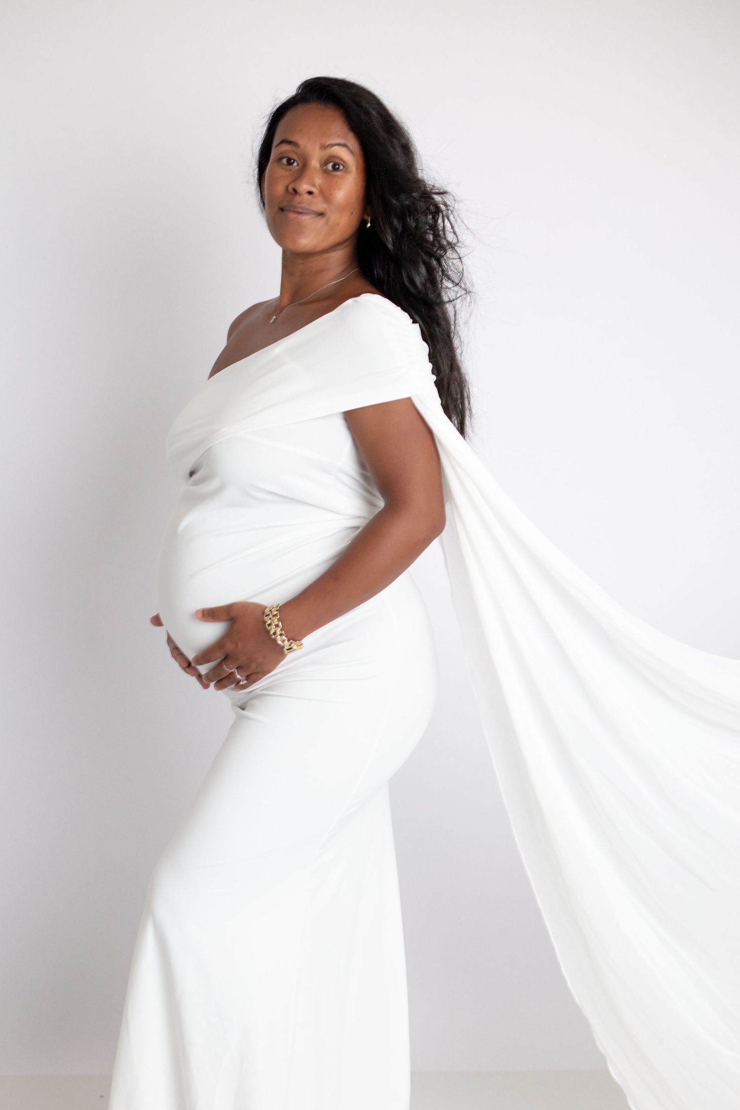 Elegant maternity portraits with flowing white fabric wrap against clean white backdrop.