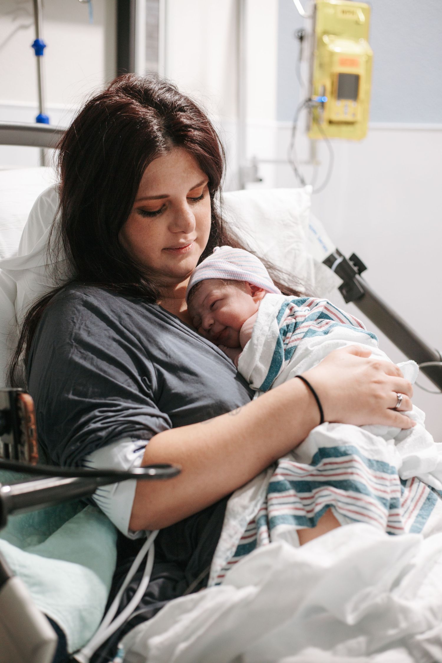 A tender moment in a hospital room as a mother embraces her newborn child while resting in bed.