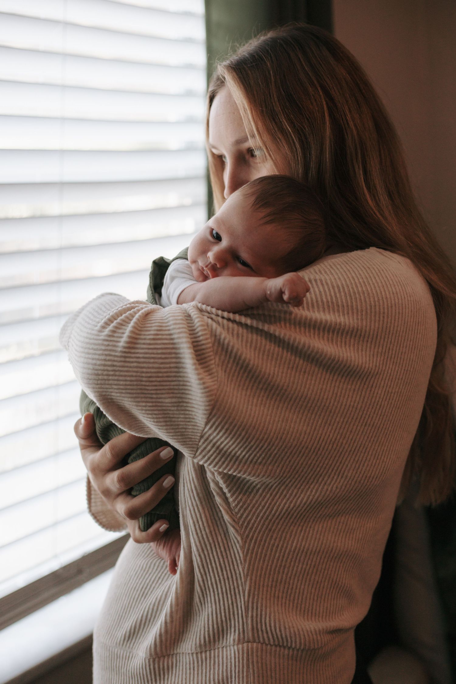 A tender moment captured near a window with soft natural lighting.