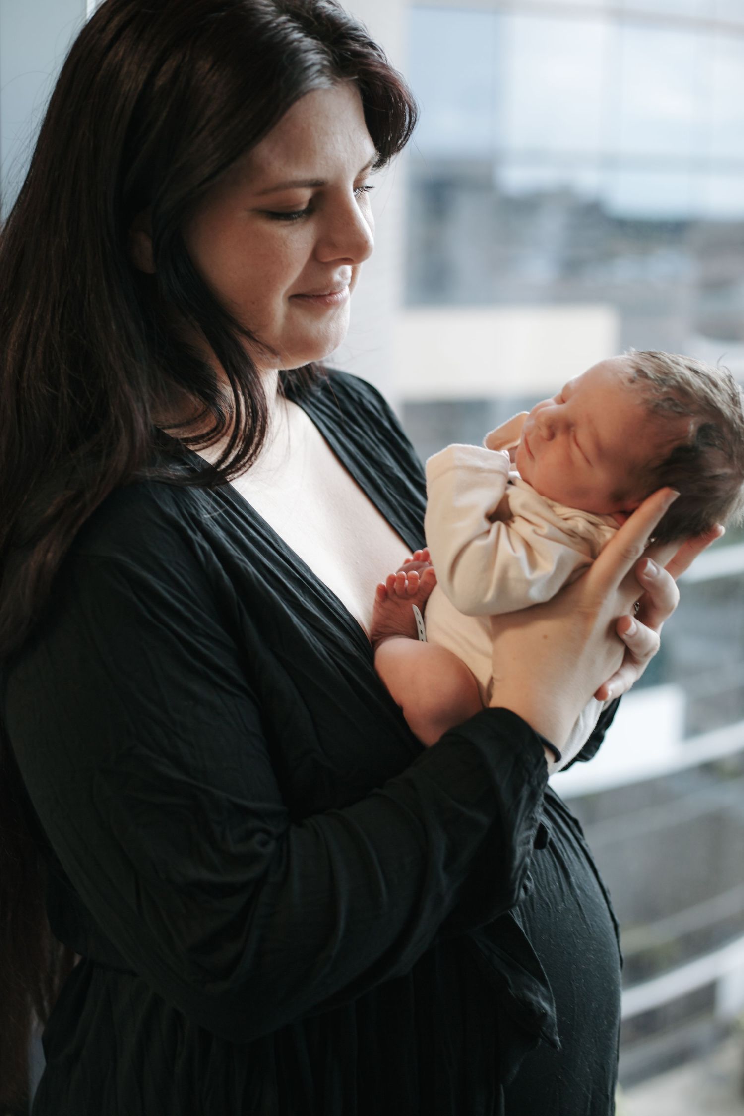 Gentle moments between parent and newborn in natural window light.