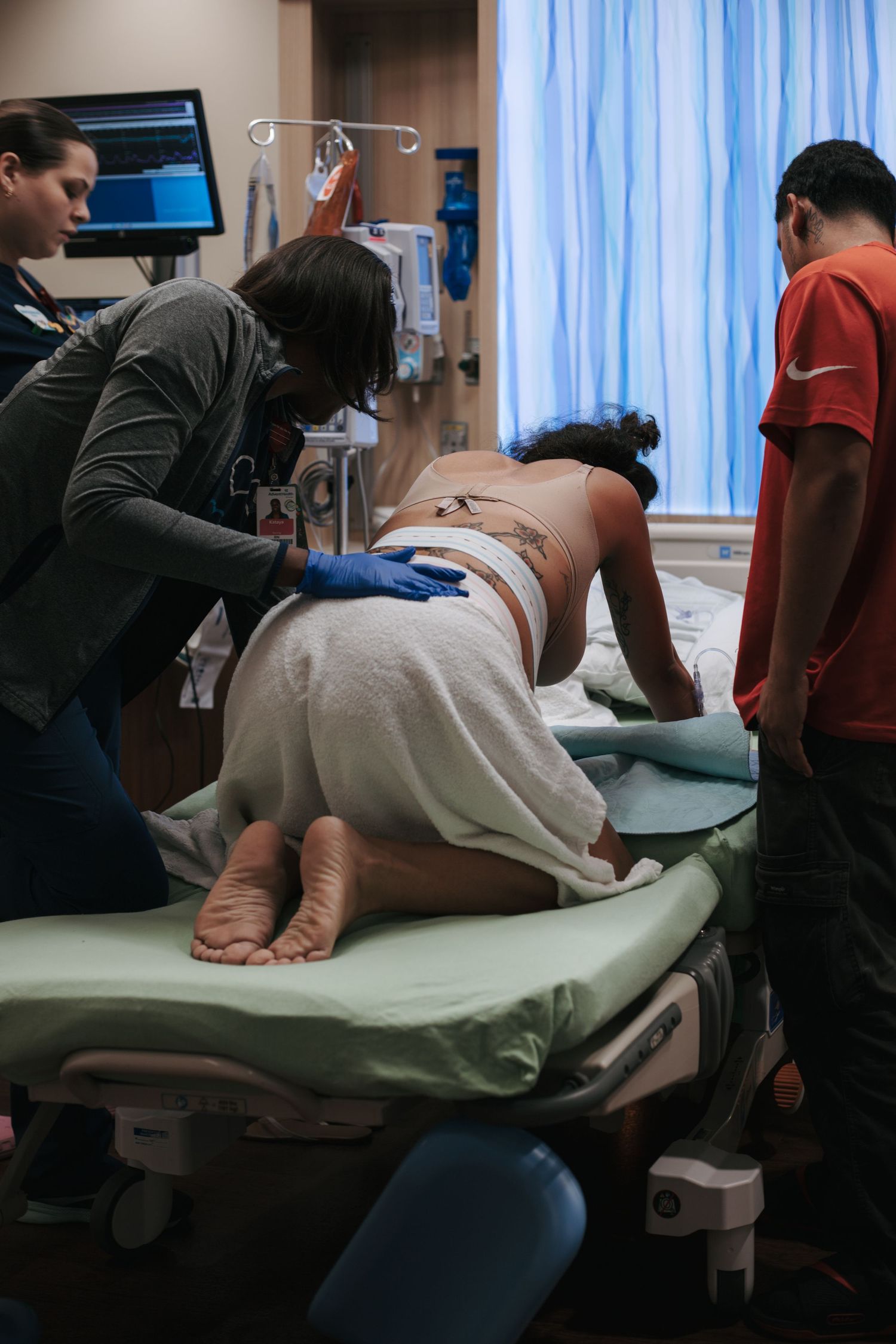 Healthcare providers assisting during a medical procedure in a hospital room.