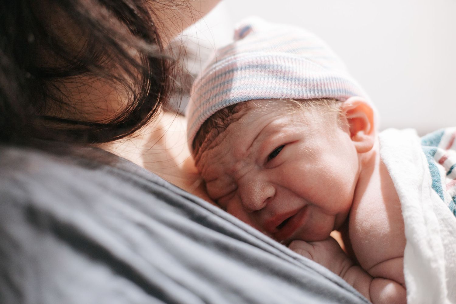 A newborn baby resting against parent in hospital after birth.