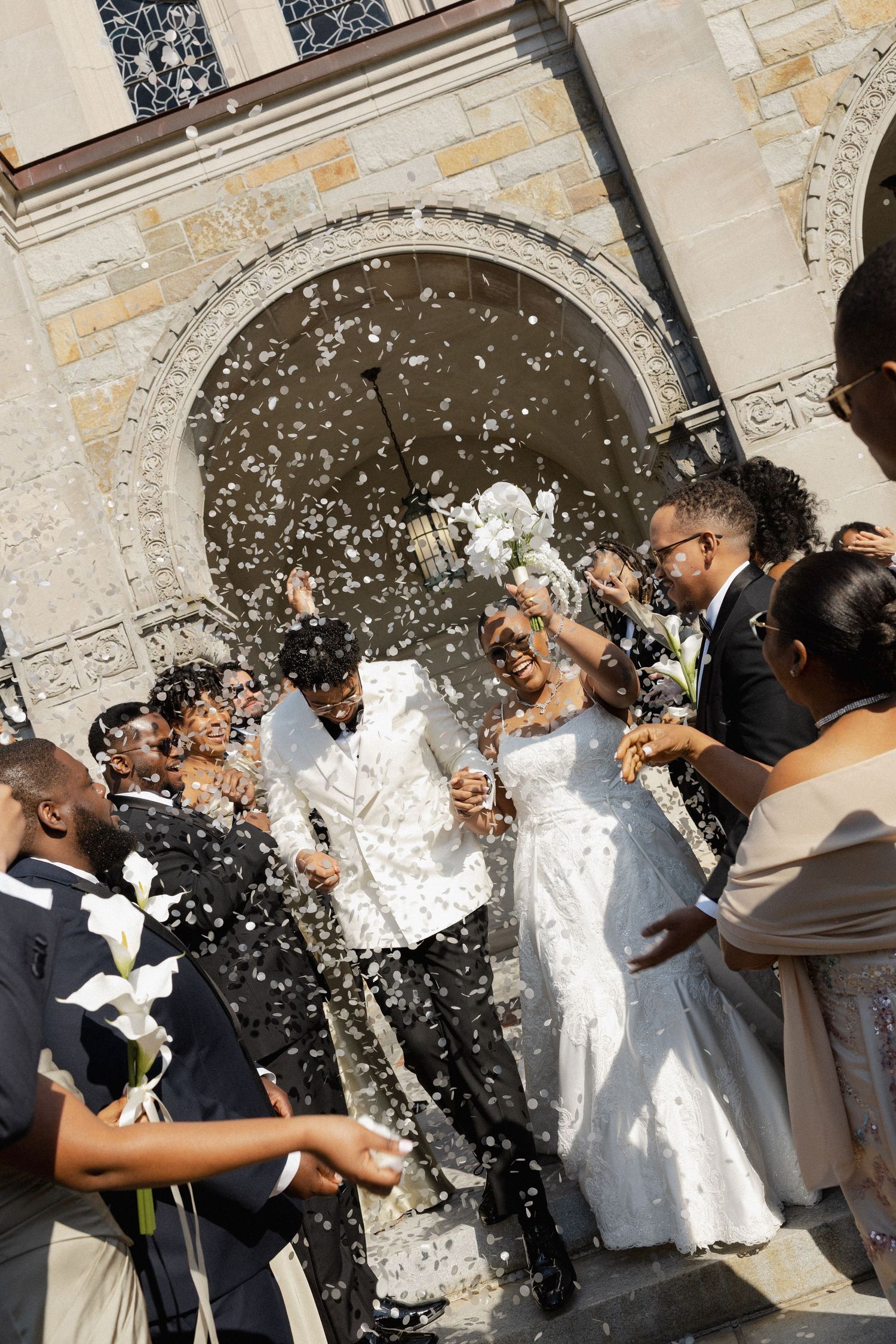 Aldrich Mansion Warwick RI - Newlyweds celebrate with wedding party as confetti showers them outside historic stone church after ceremony.