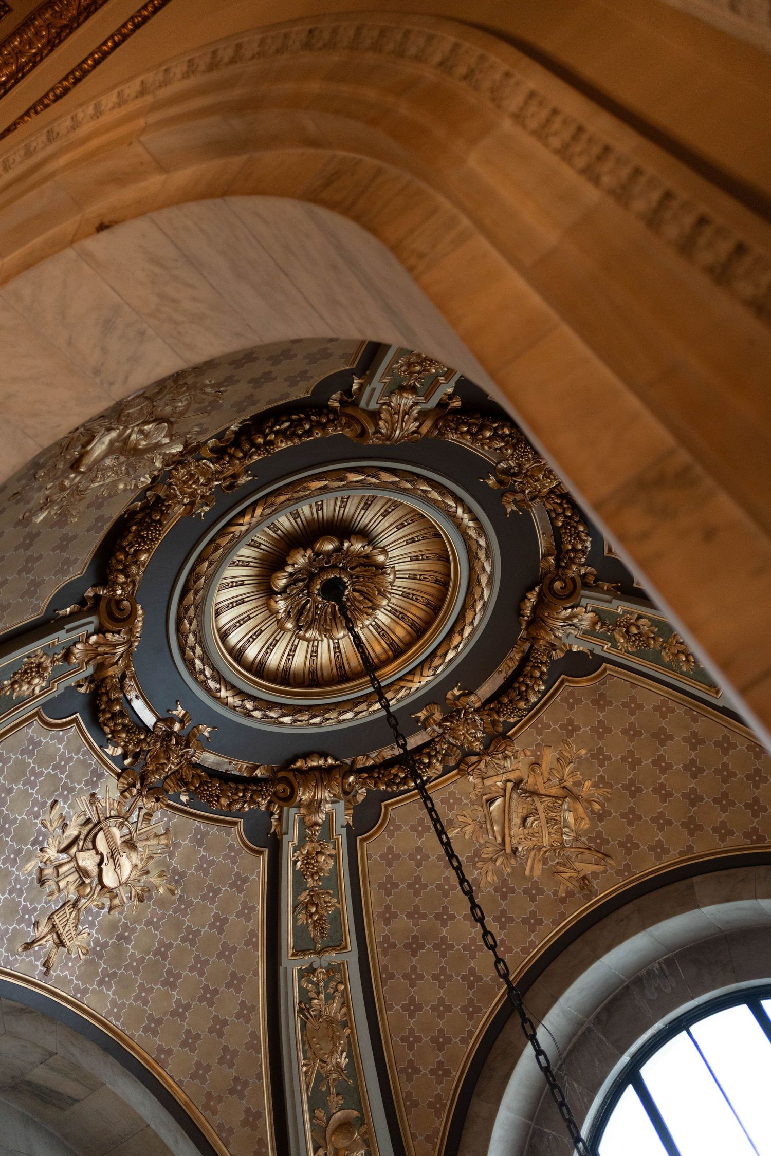 Ornate gold and blue decorative ceiling medallion with chandelier in a historic classical building.