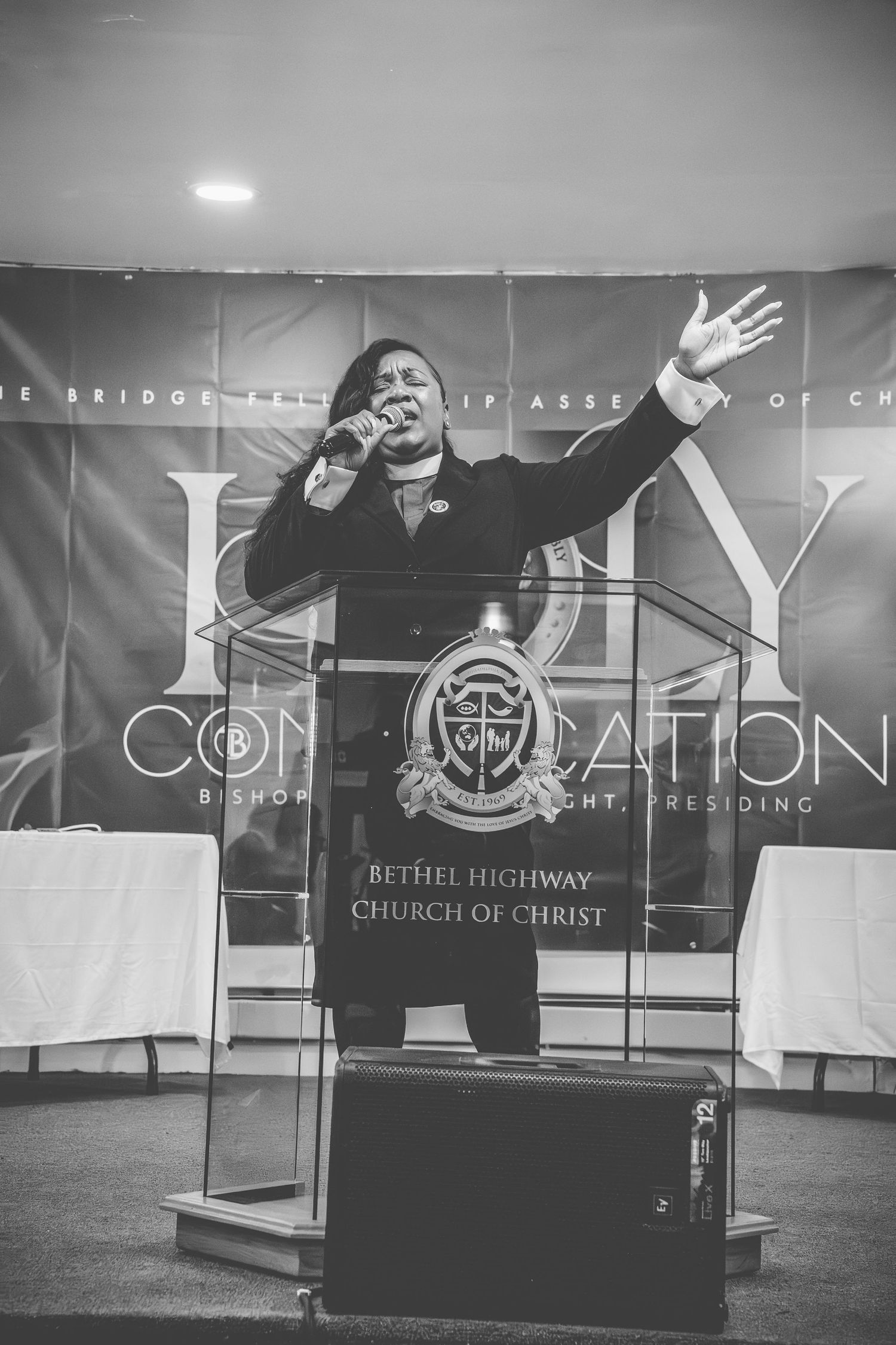 Energetic worship leader performing on elevated church platform in black and white.