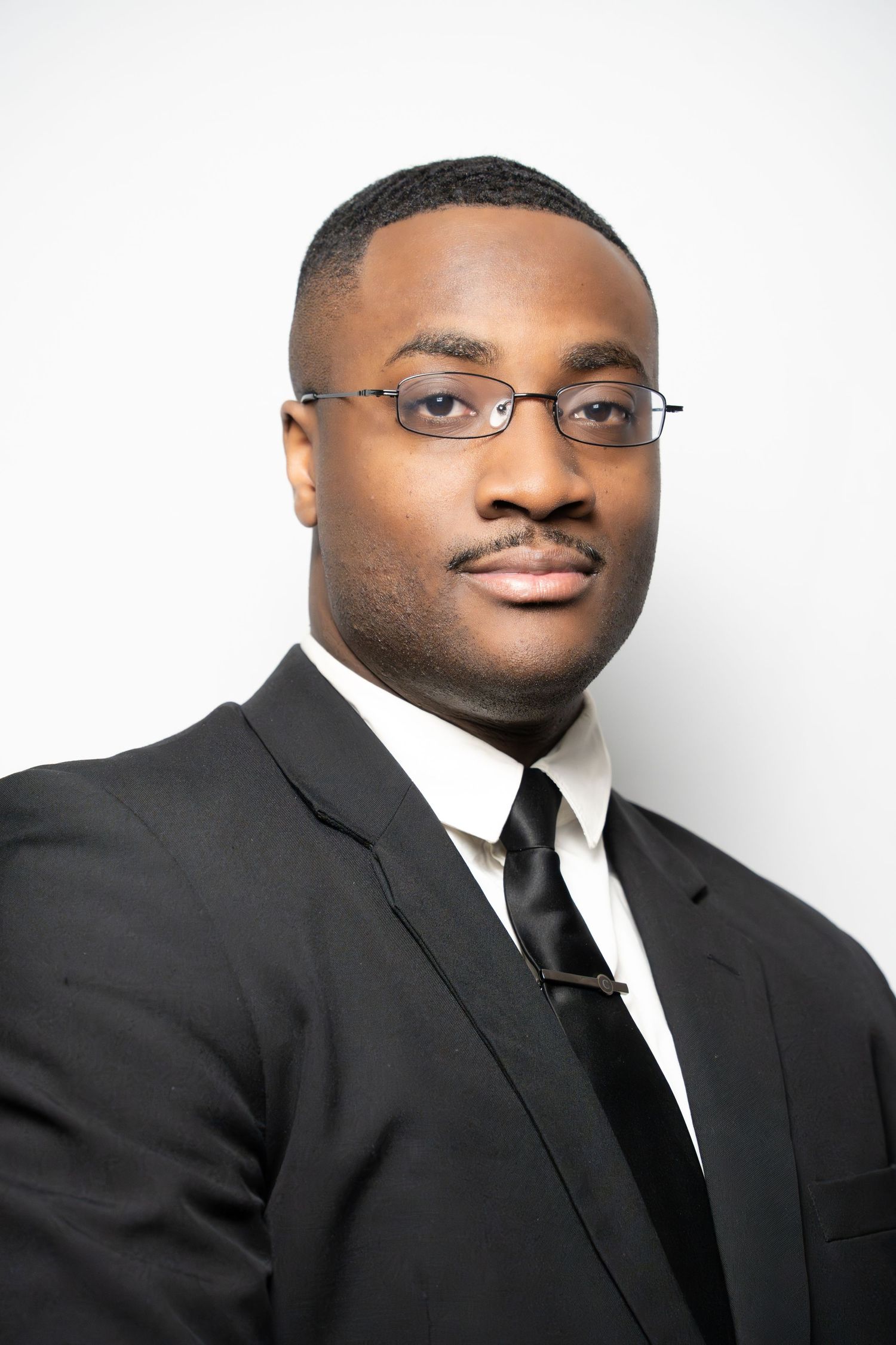Professional headshot series showing person in black suit and tie against white background from different angles.