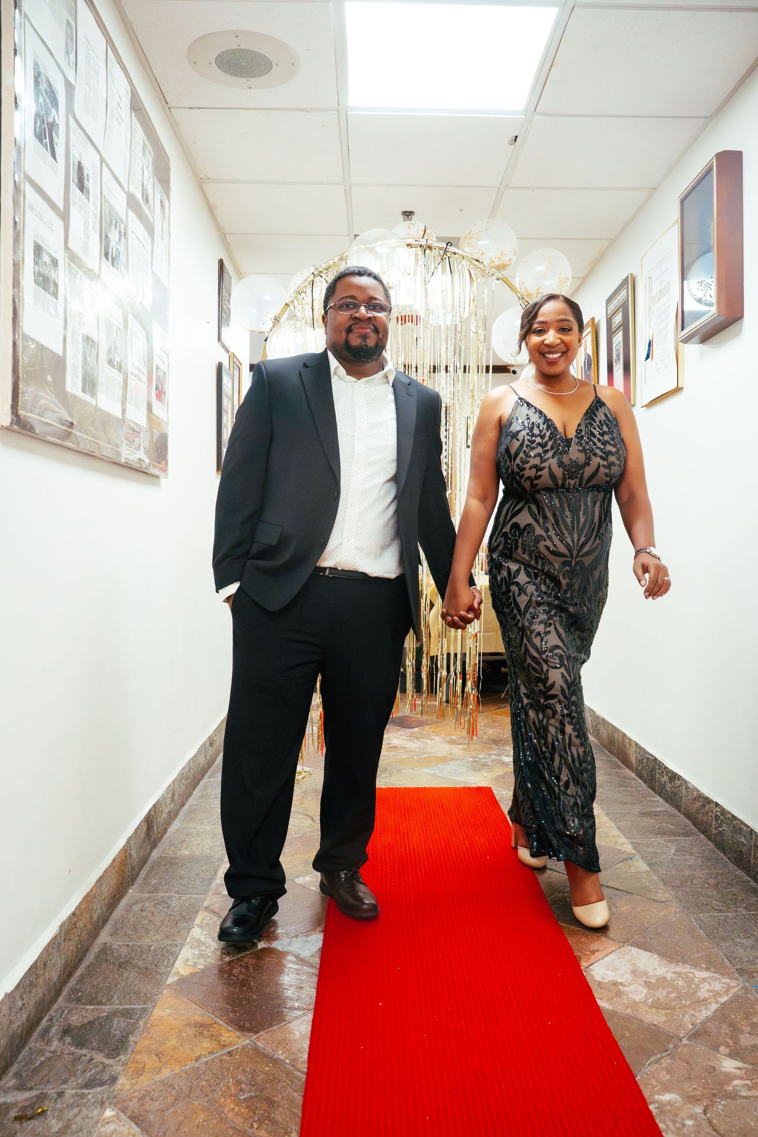 A couple walks together down a hallway with a bright red carpet, shown in a sequence of four similar photos.