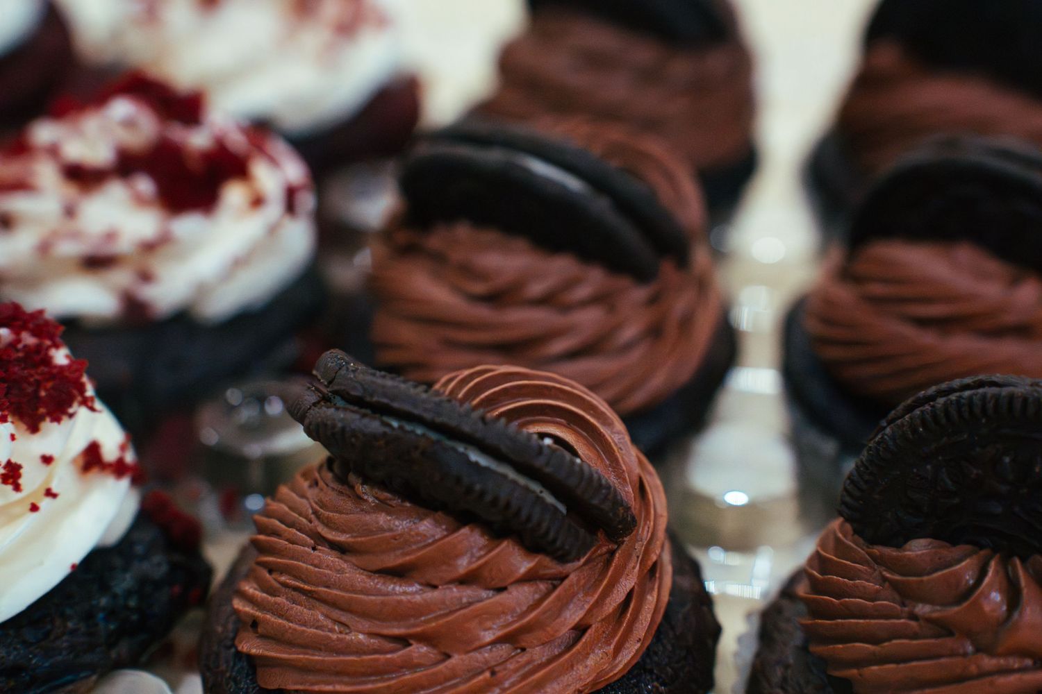 Close-up of chocolate cupcakes with white frosting and cookie garnishes.