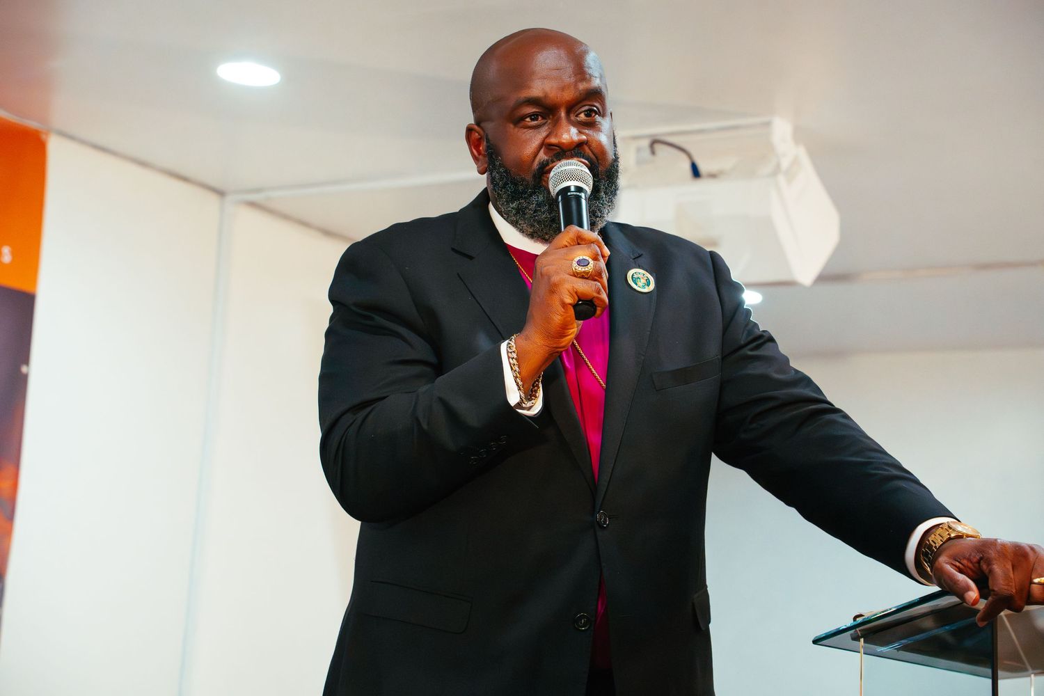 A speaker in a suit and red tie gestures passionately while delivering a presentation on stage.