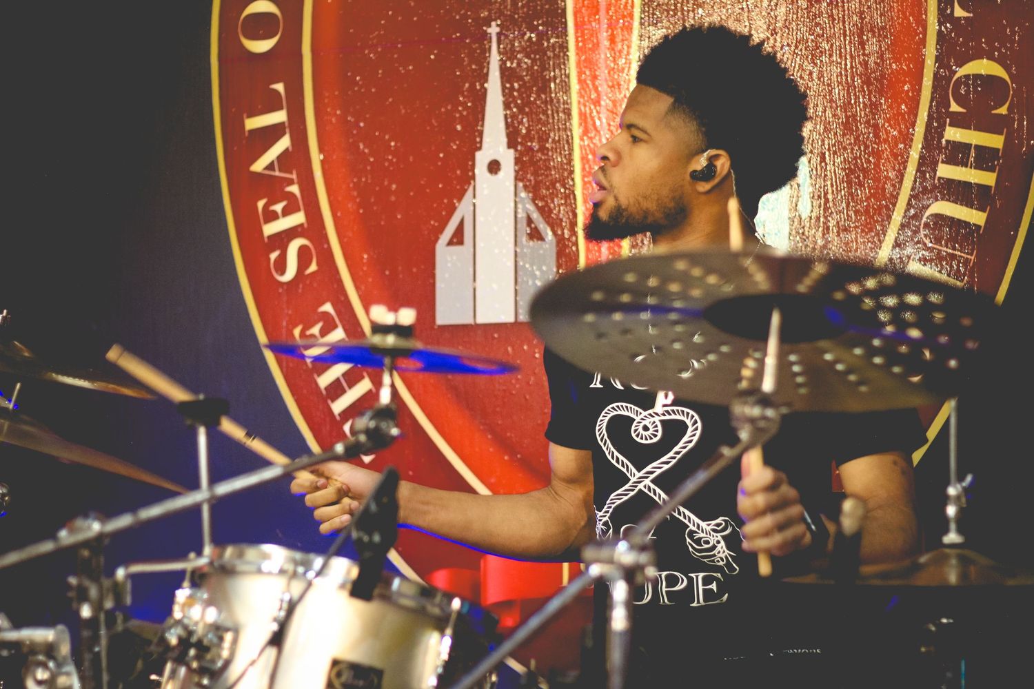 Musicians performing on stage with vibrant red lighting and dramatic stage effects.