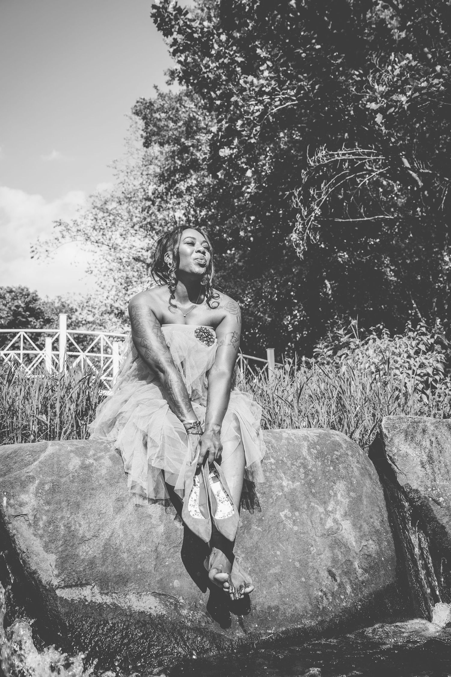 A dreamy black and white portrait of someone sitting on a rock in an outdoor setting.