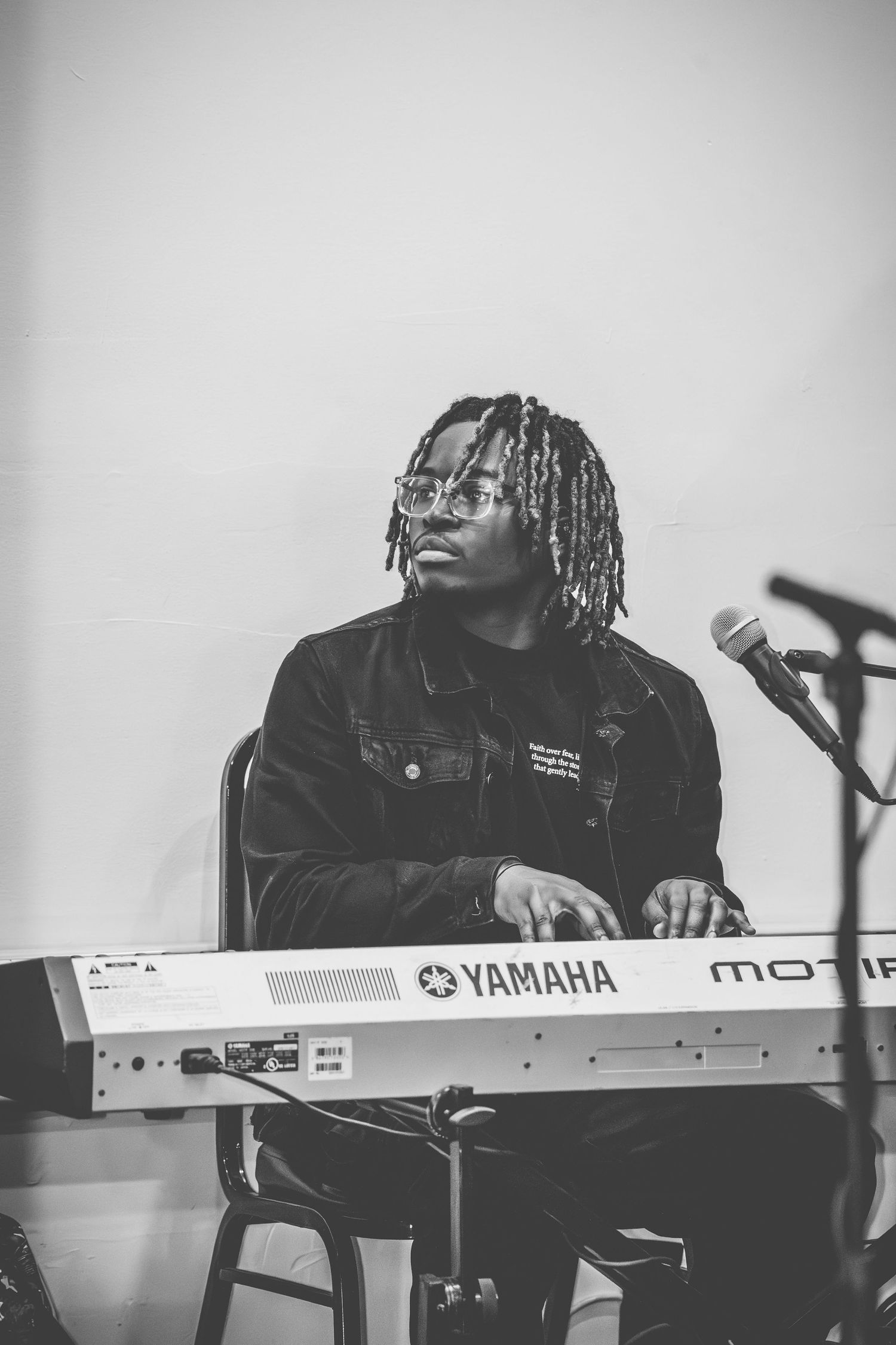 A musician plays a Yamaha keyboard in a monochrome performance photo.