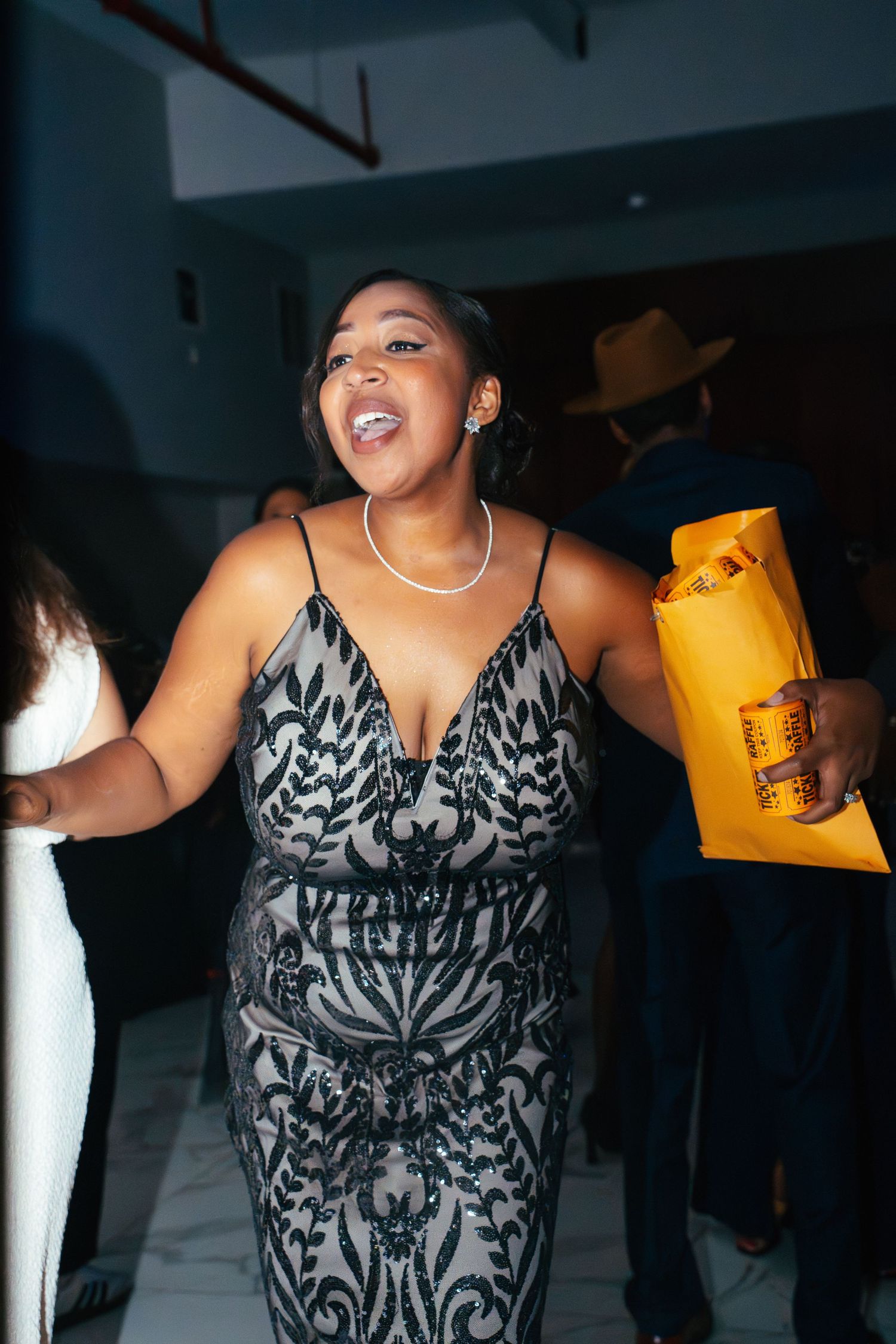 A person in a black and white patterned dress dances joyfully at a party.