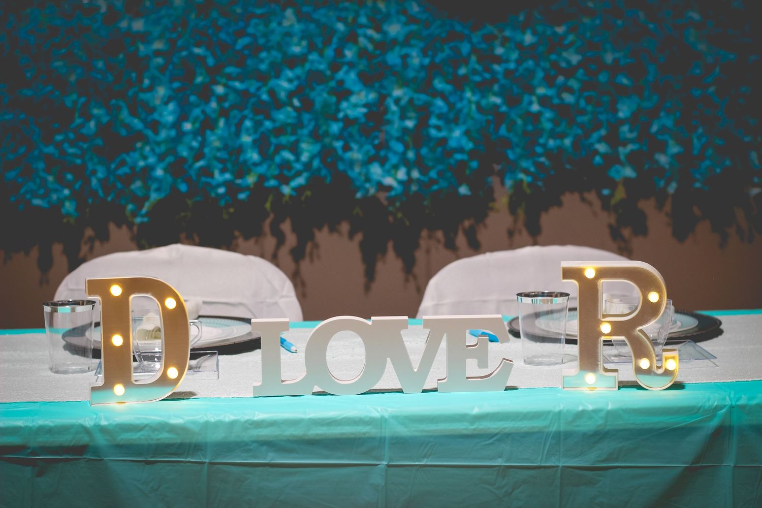 Decorative gold letters and numbers arranged on a turquoise table setting.