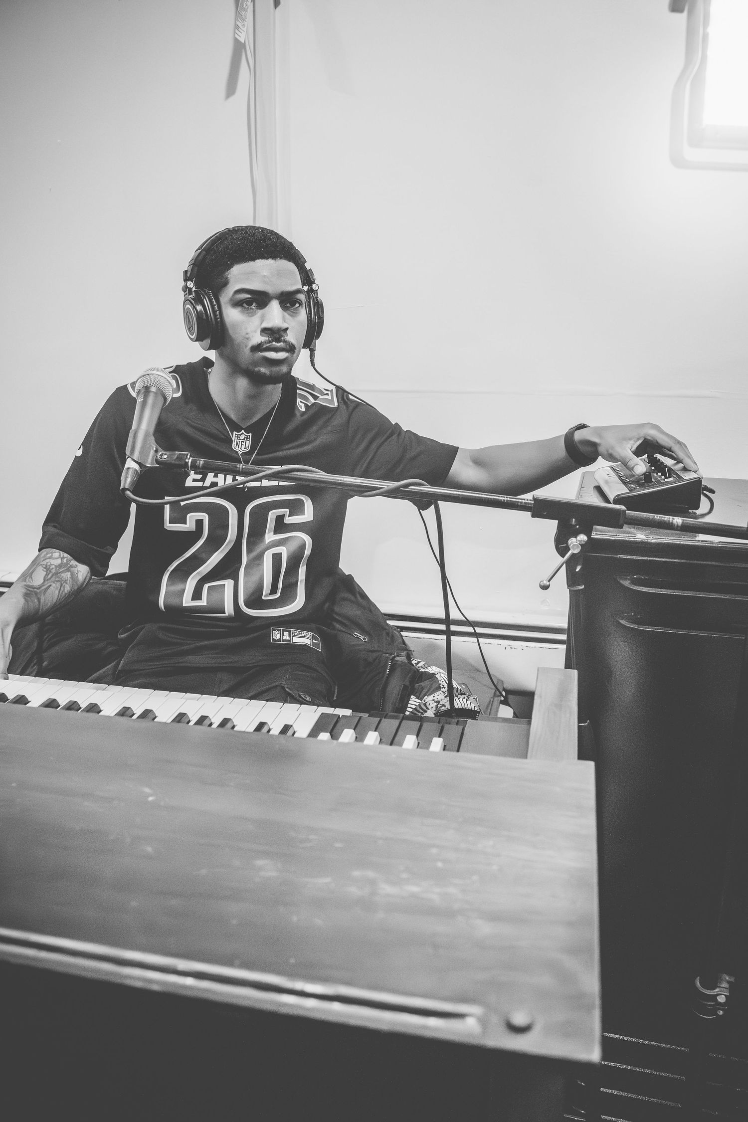 Musician in a black jersey with number 20 plays keyboard in black and white photograph.
