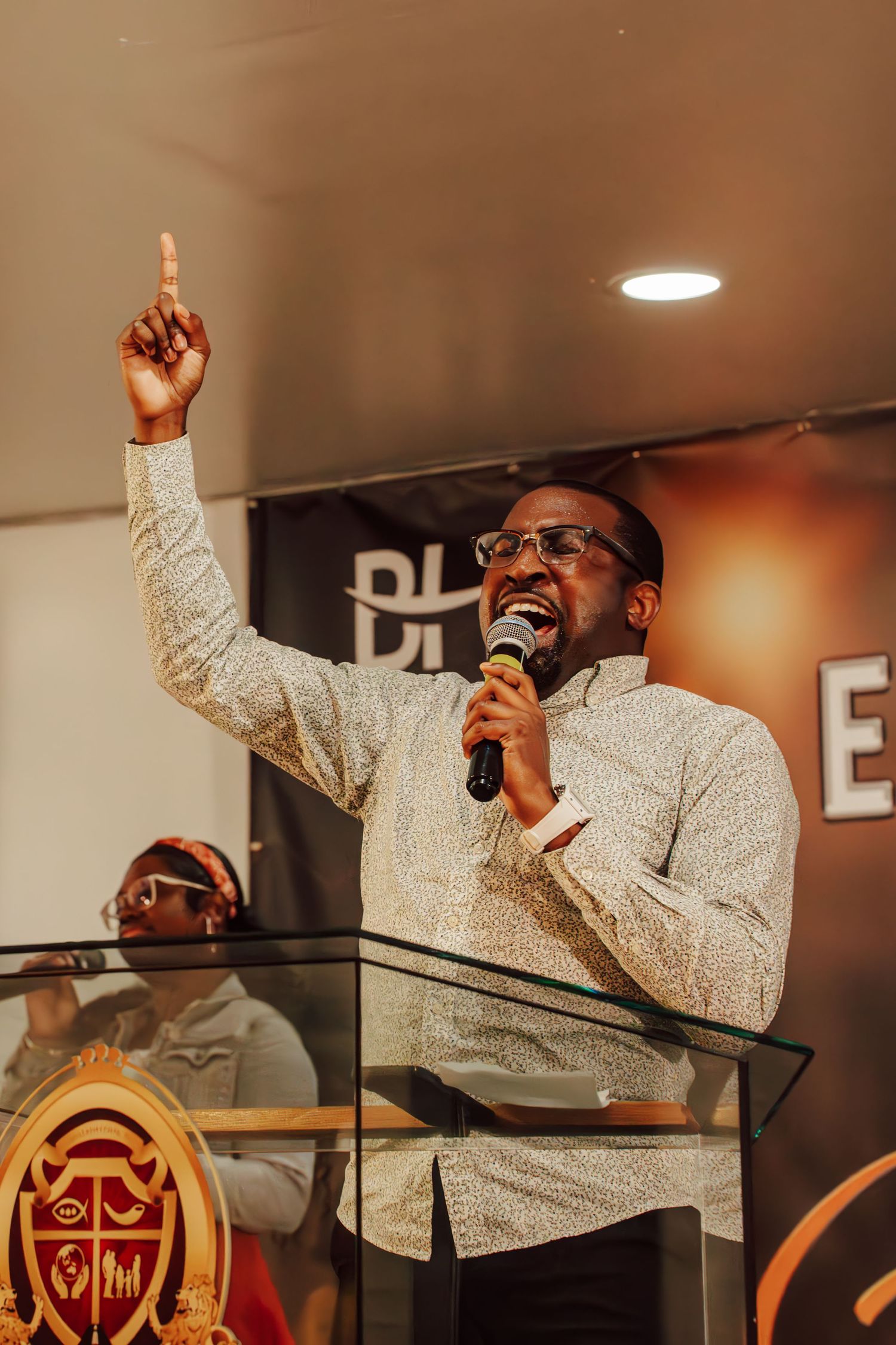 Performer in white patterned shirt passionately singing during a worship service.
