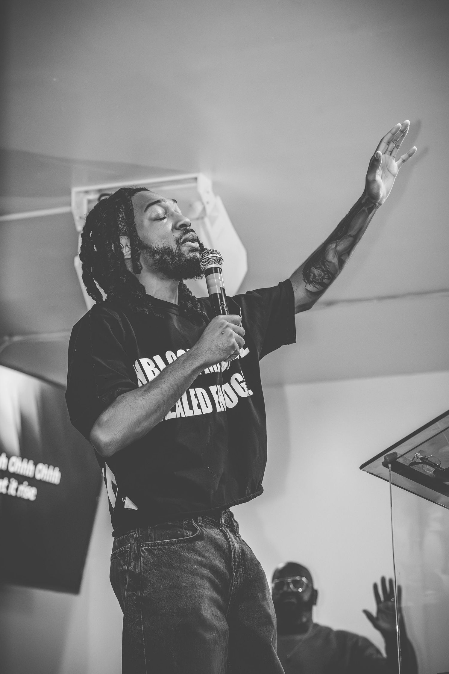 Performer in black clothing sings passionately on stage during an energetic musical performance.