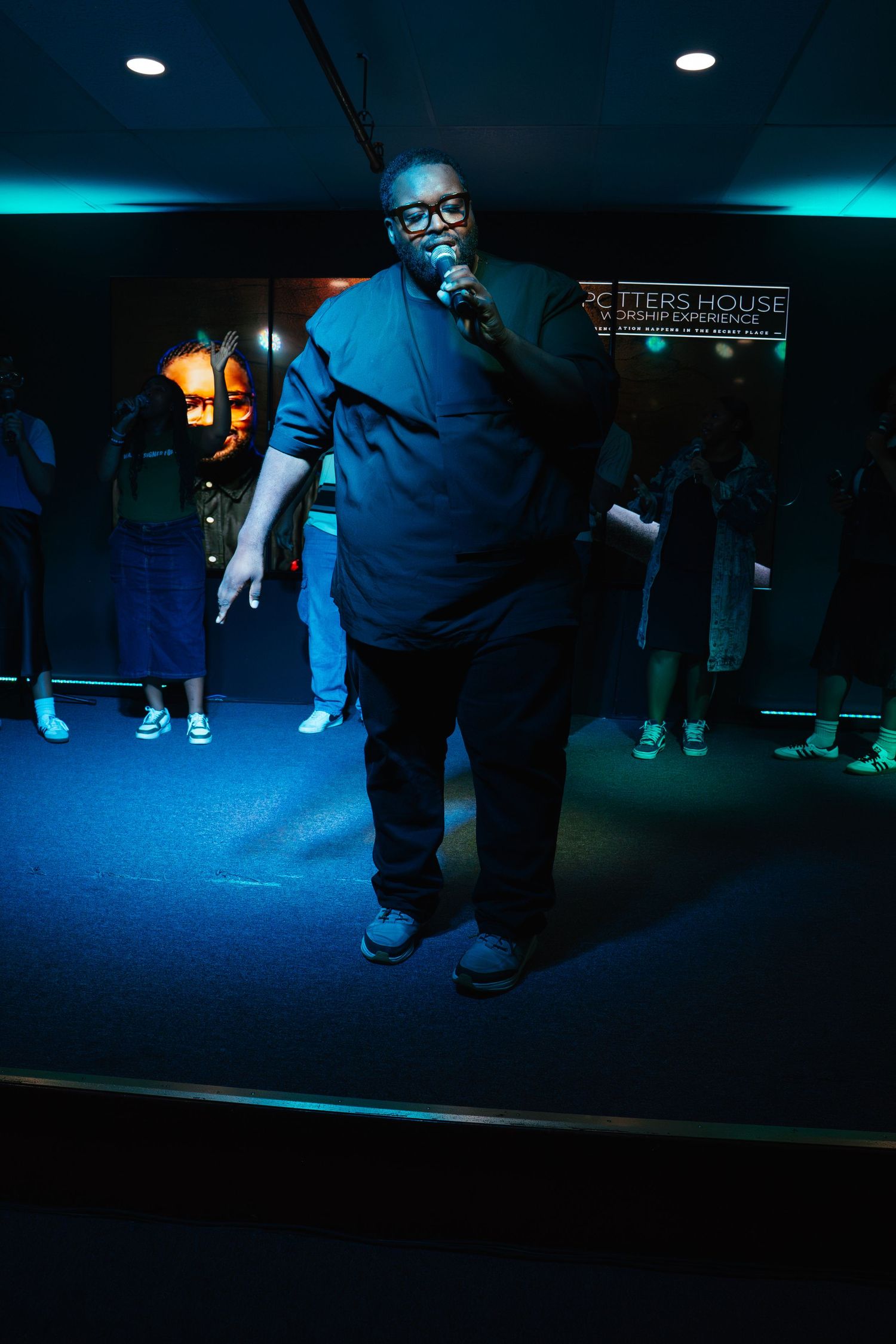 A dimly lit dance performance with dramatic blue lighting and silhouetted figures on stage.