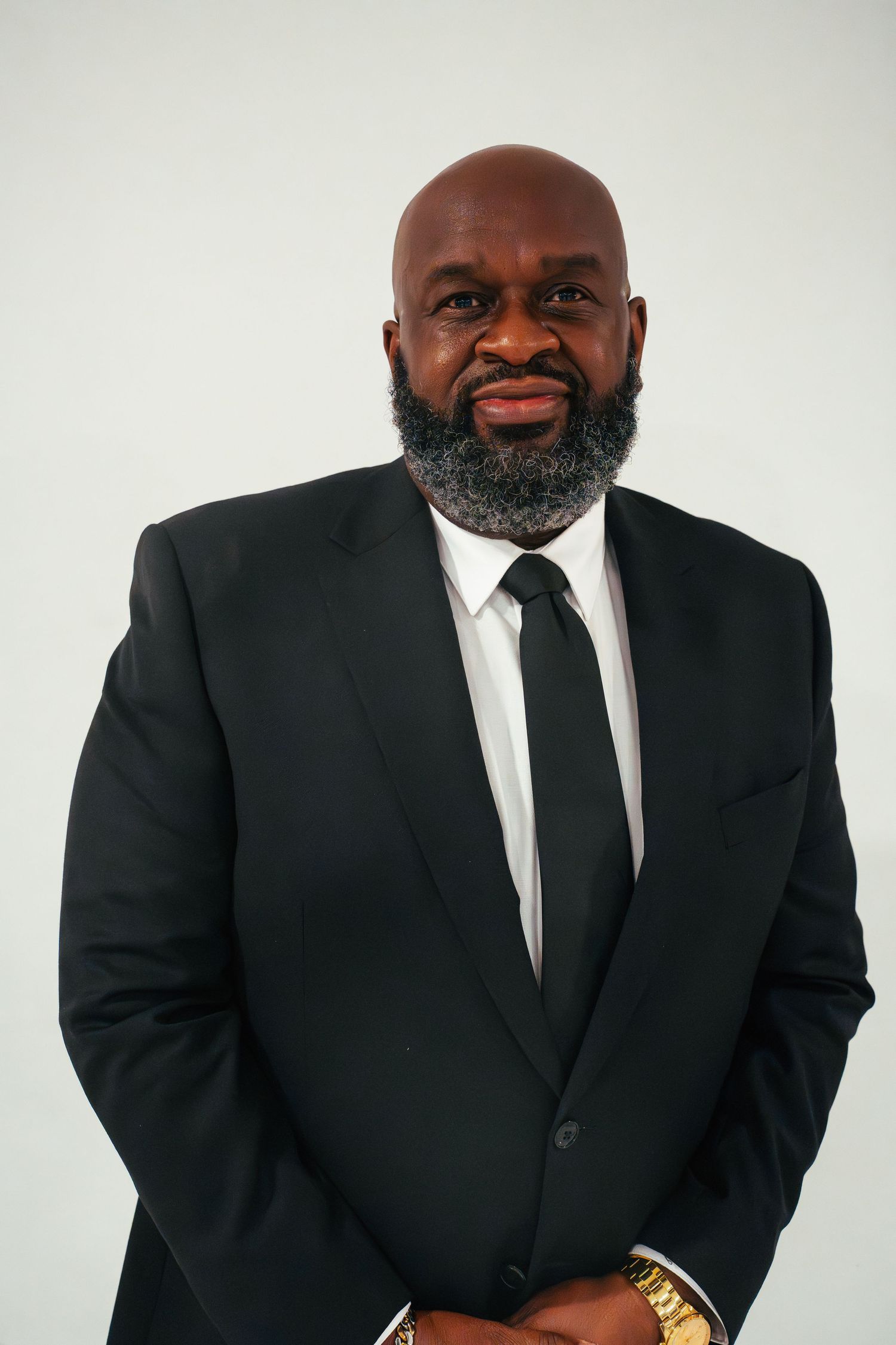 Professional studio portrait against white background in formal black suit and tie.