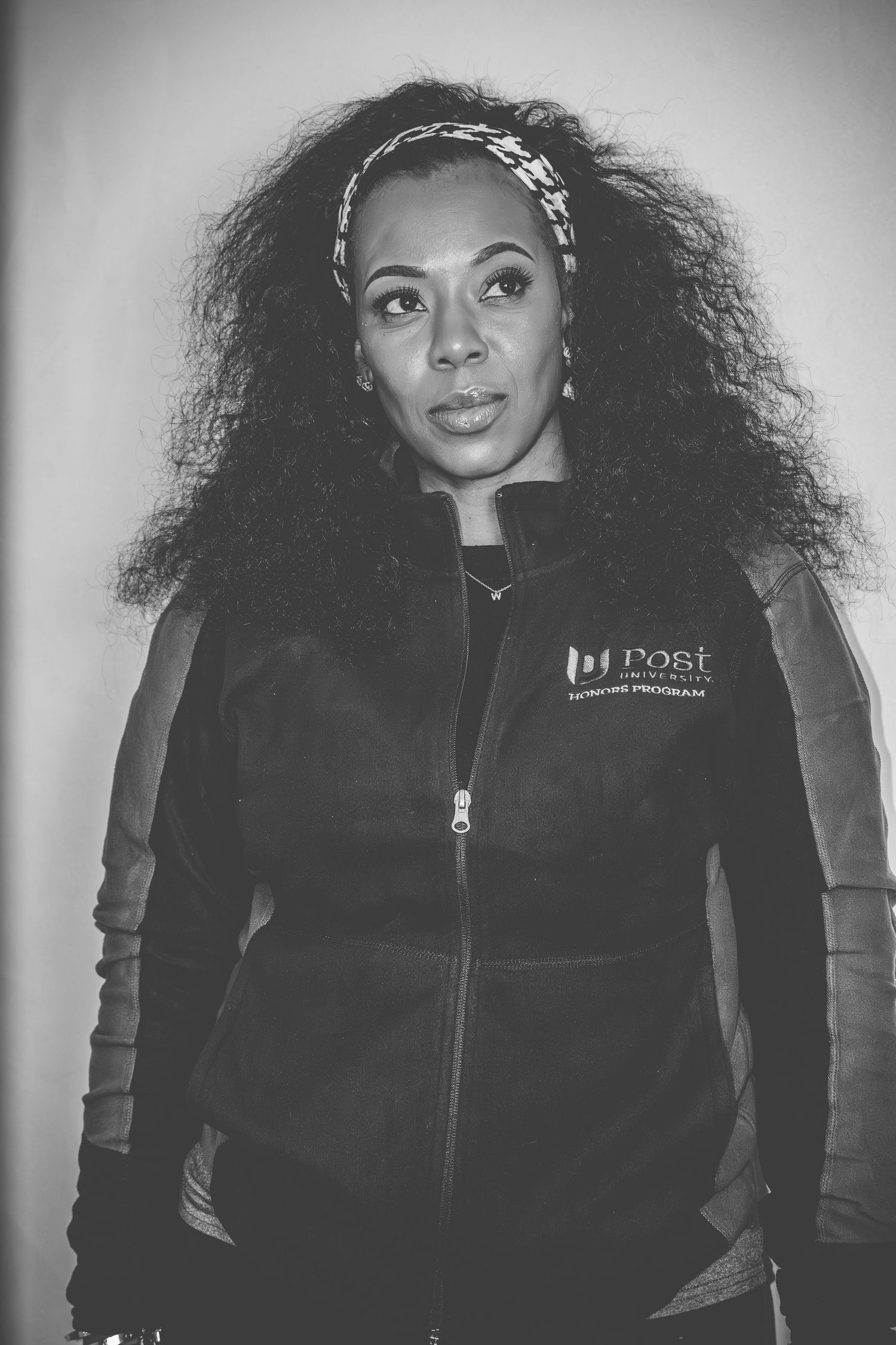 A series of black and white portraits showing a person with curly hair wearing a black winter vest in different poses.