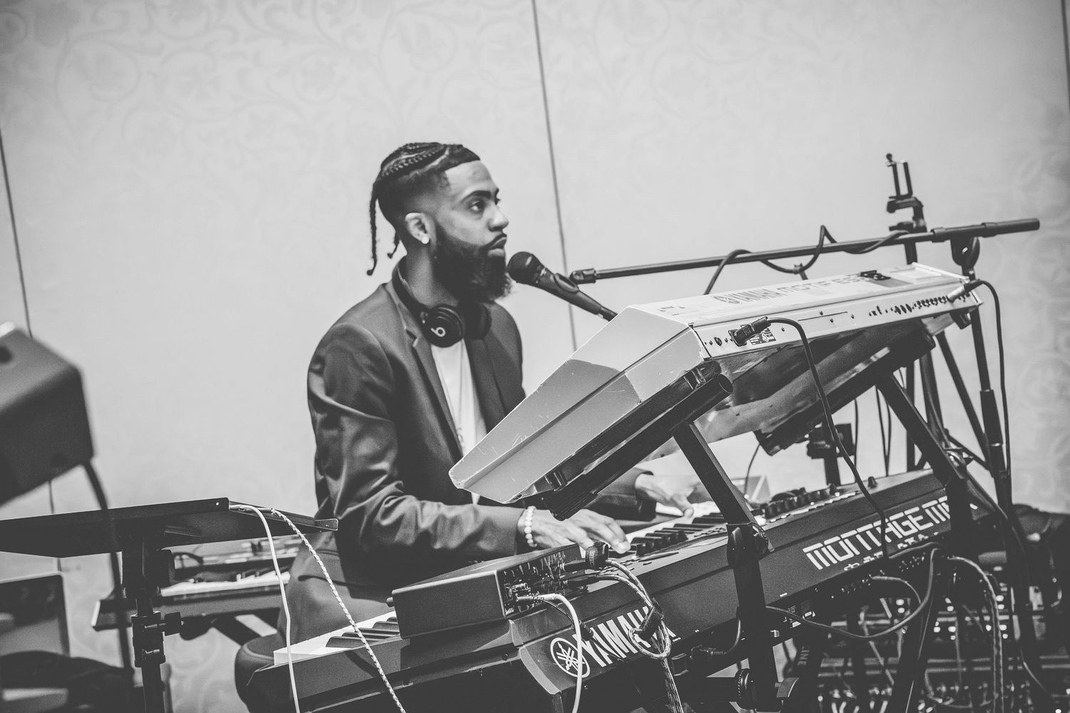 Musician performing at a keyboard setup with electronic equipment in black and white.