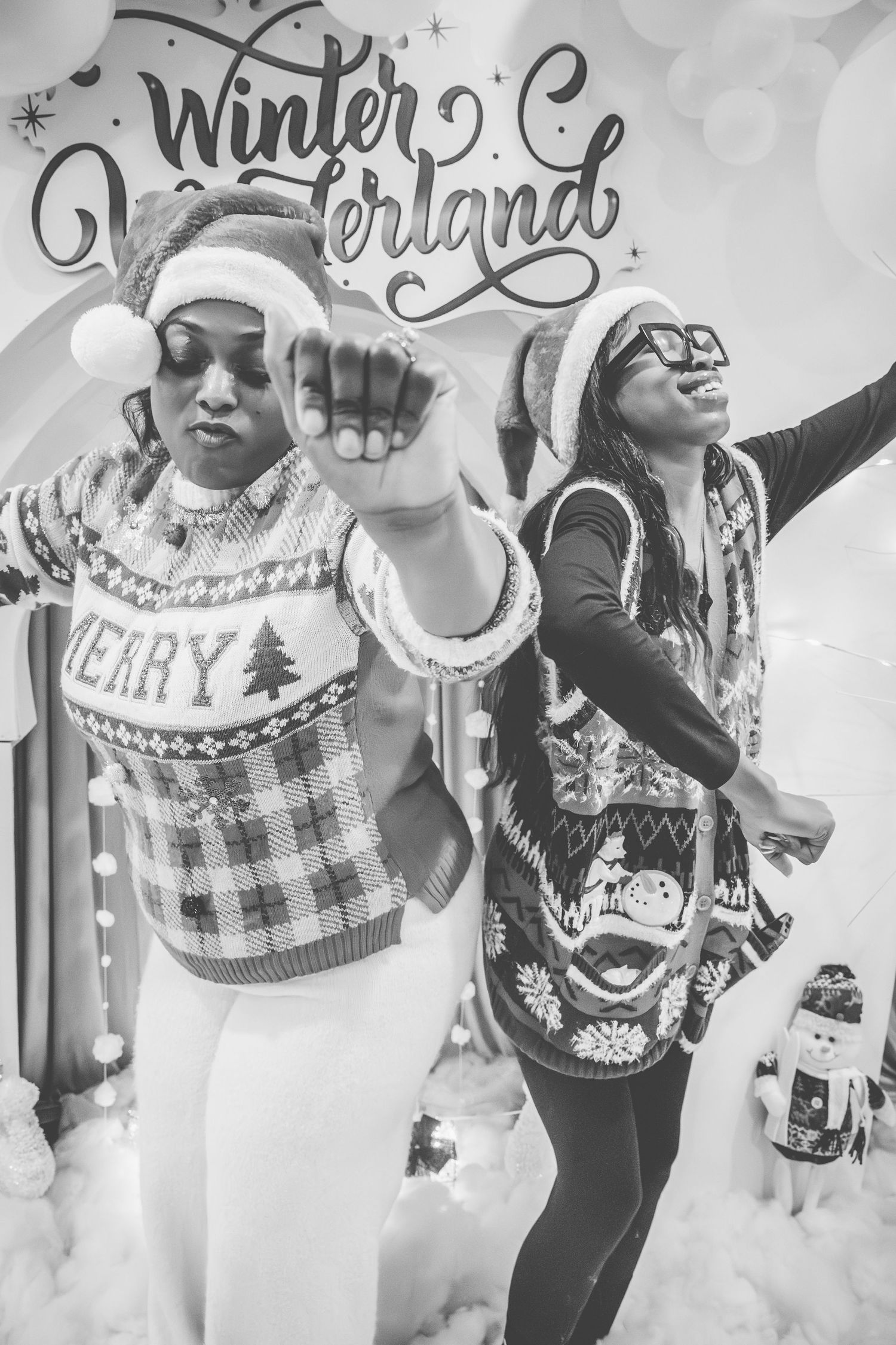 Two people pose energetically in winter sweaters against a festive Winterland backdrop.
