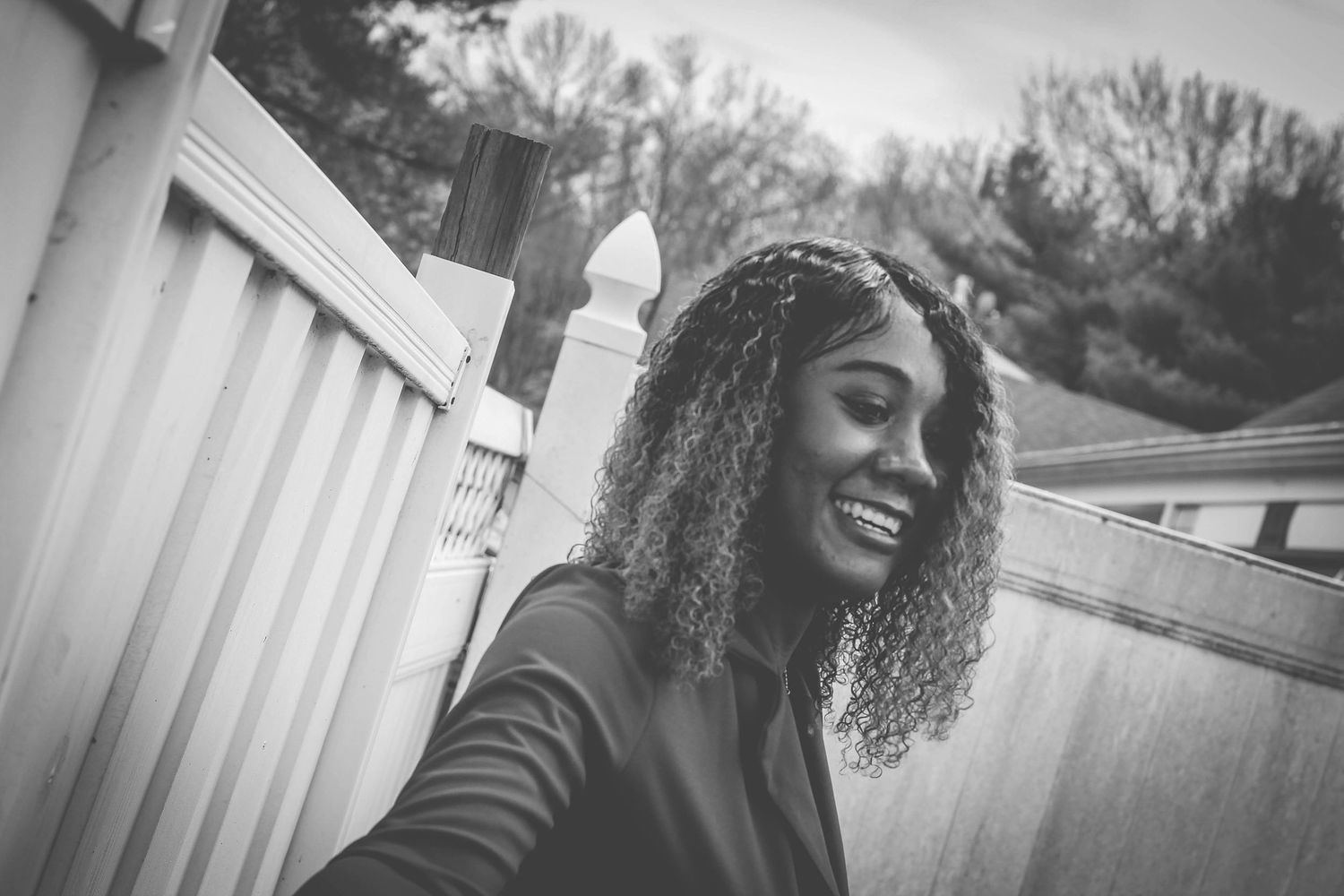 A series of black and white portraits showing joyful expressions and natural curly hair against outdoor backgrounds.