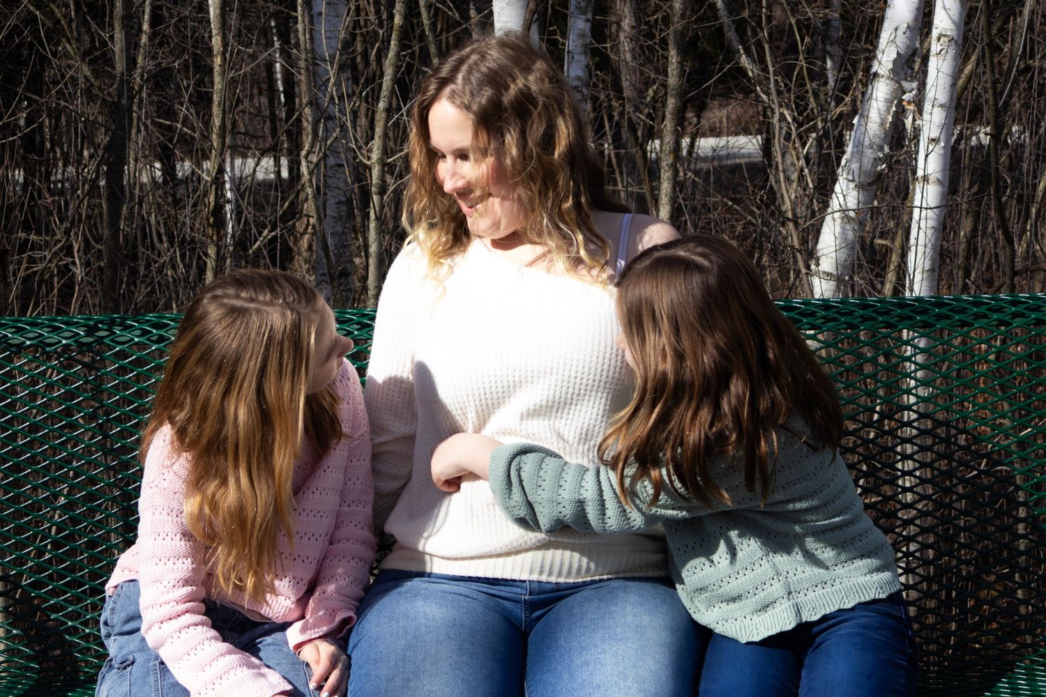 A mother shares a candid moment with her two daughters during a family photography session.