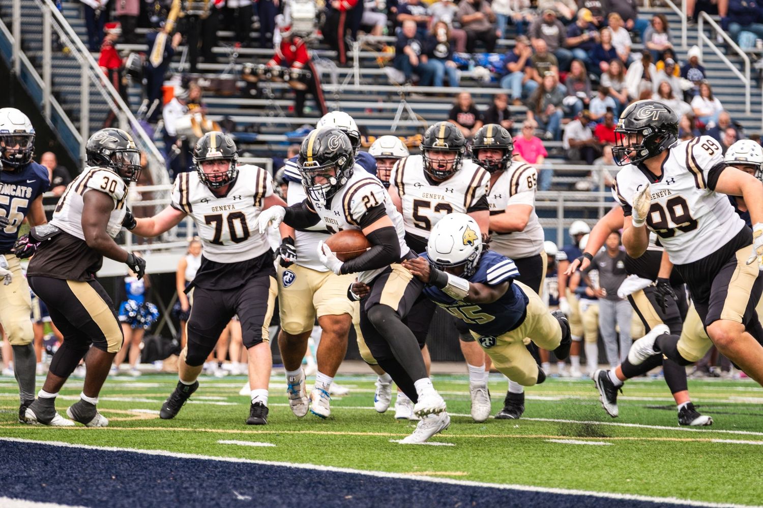 Geneva football team blocks during daytime game action.