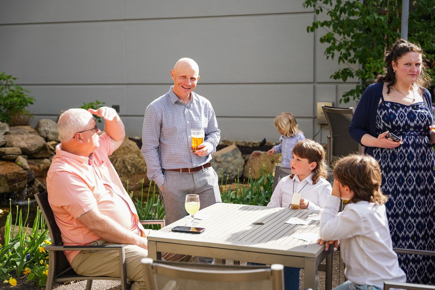 Family gathering outdoors at a wedding reception with children and adults socializing at a patio table.