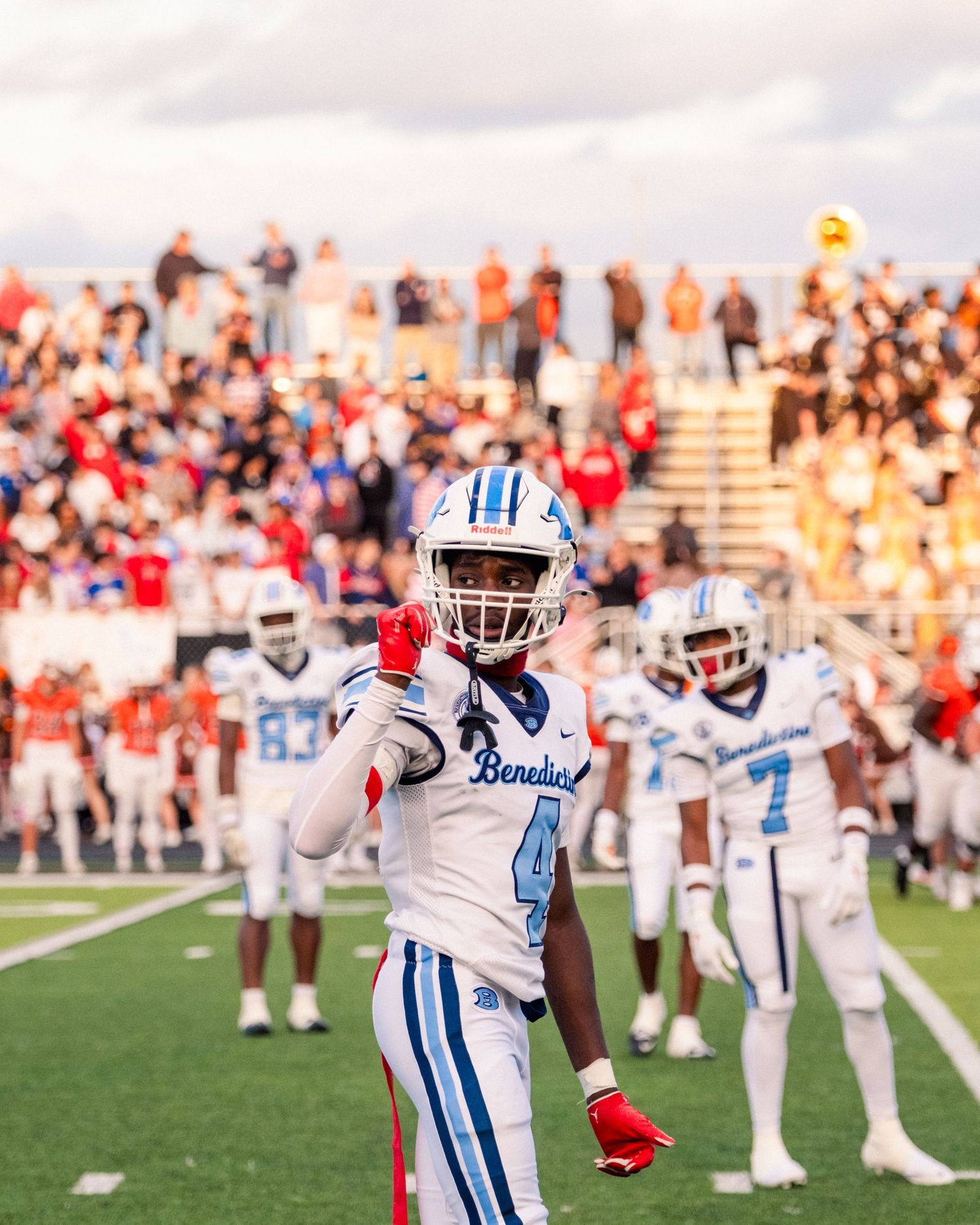 Benedictine football player number 4 signals to teammates on the field before a packed crowd.