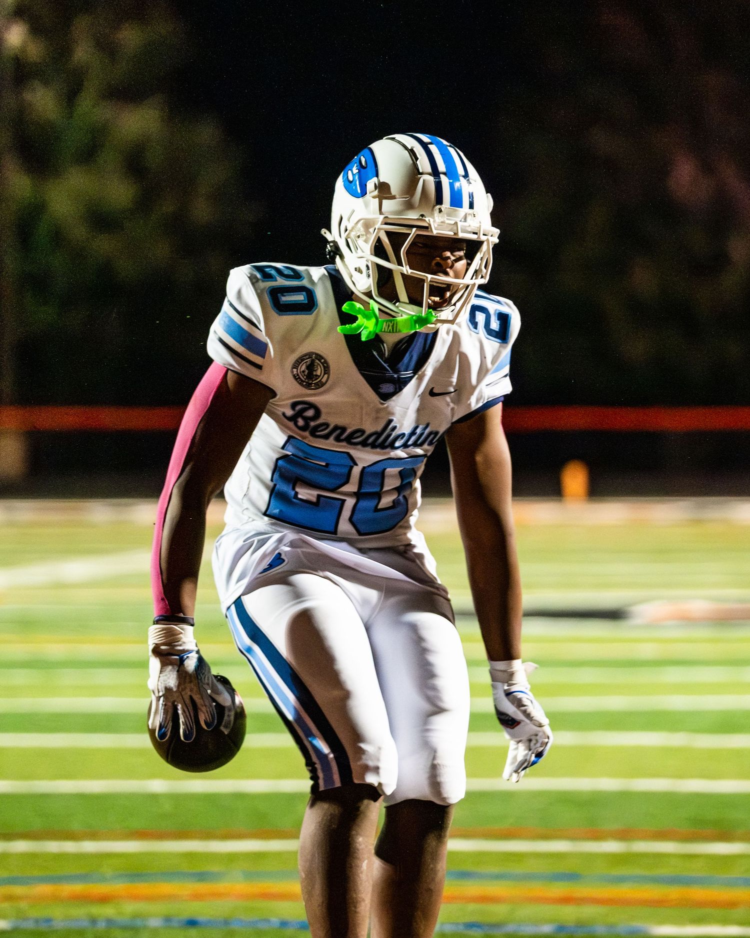 Benedictine football player #20 in white uniform poses on field.