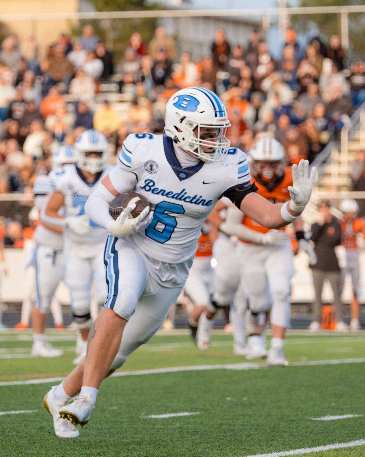 Benedictine football player number 6 runs with the ball during a competitive game.