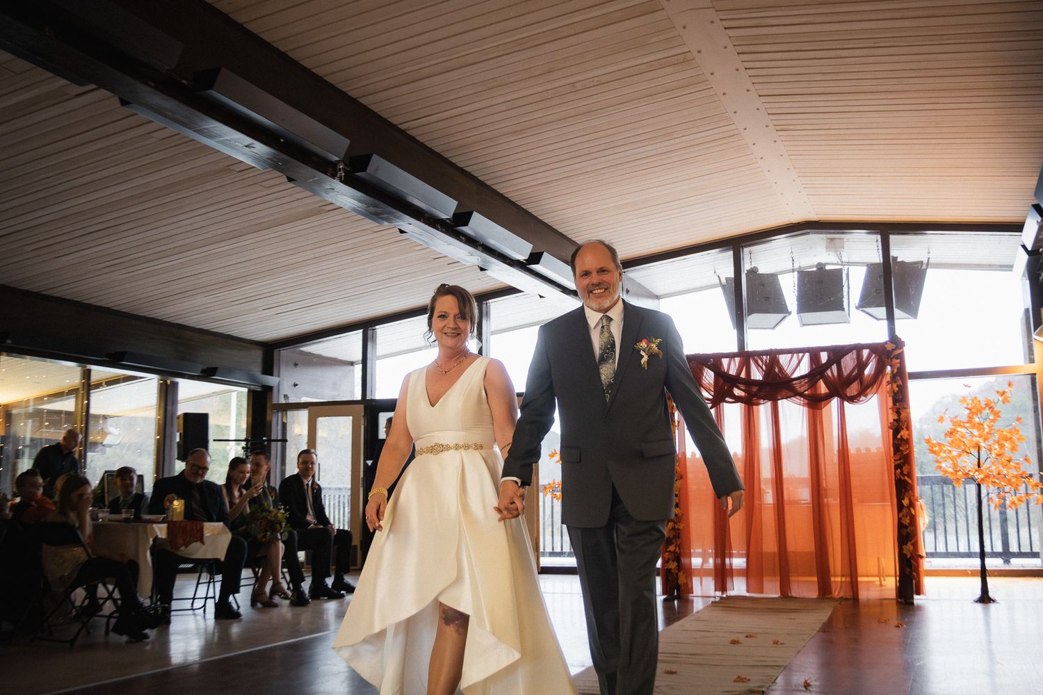 Happy bride and groom walking hand in hand after their wedding ceremony in a modern venue.