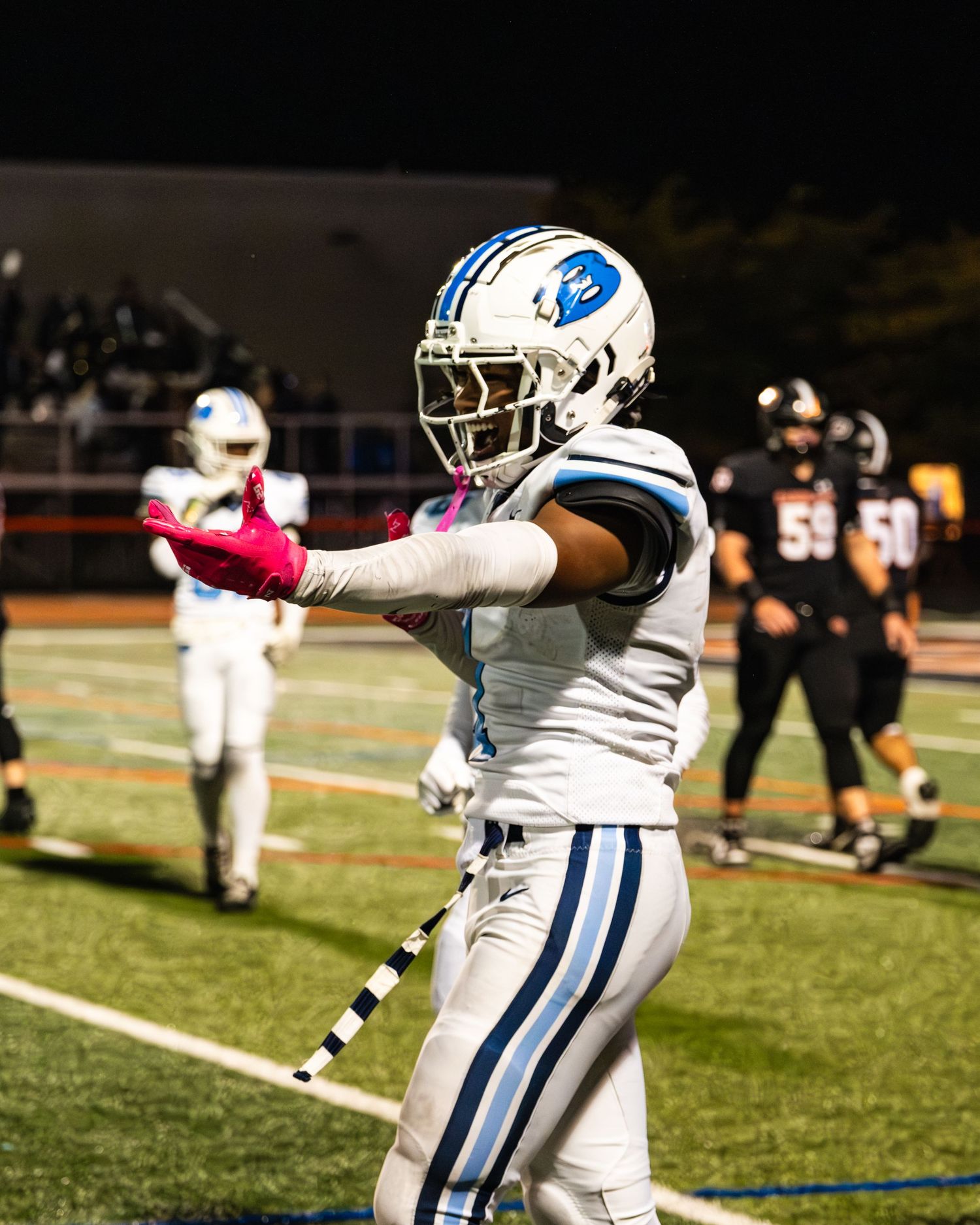 Benedictine football player gestures on field during night game.