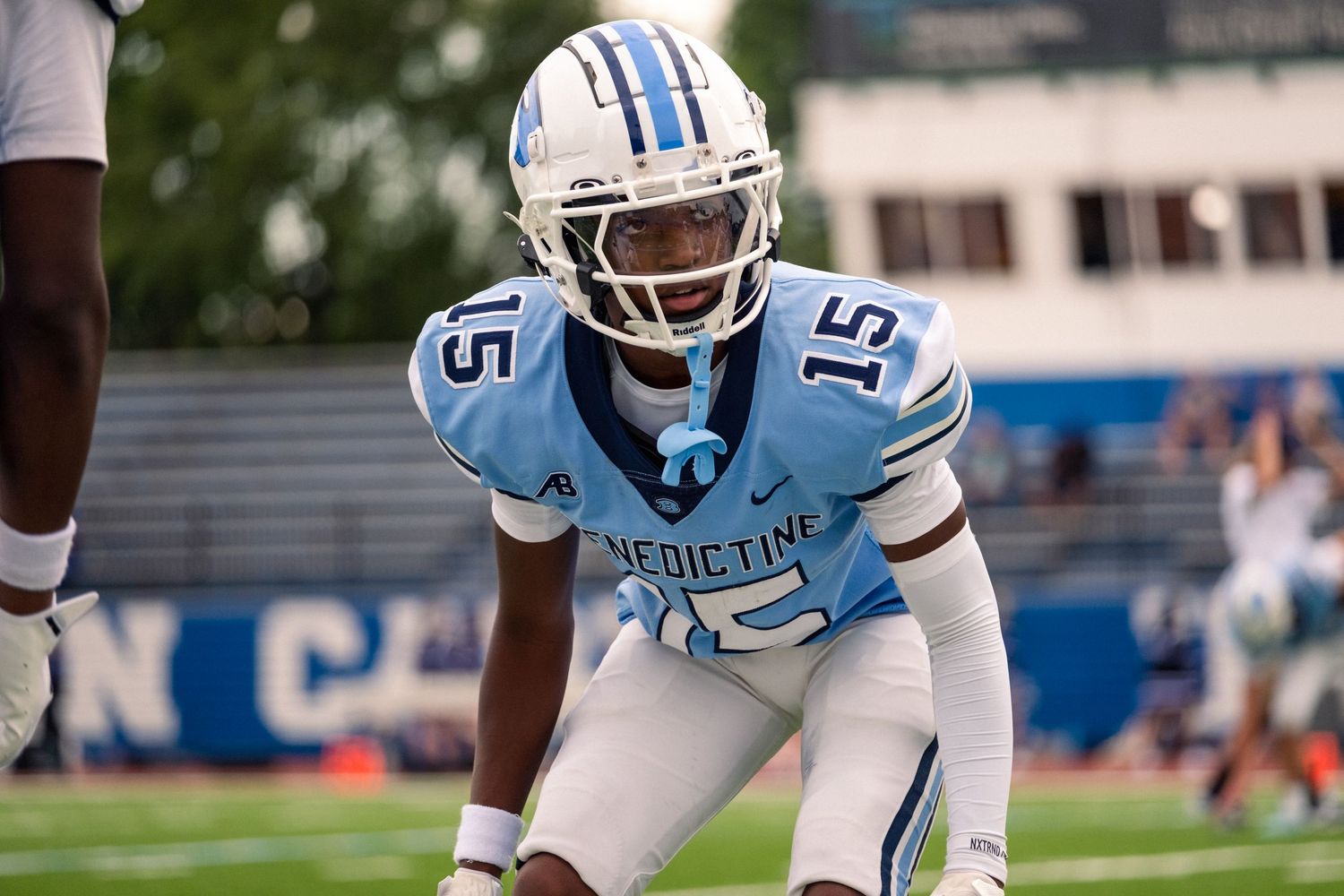 Benedictine football player number 15 in light blue uniform crouches in ready position.