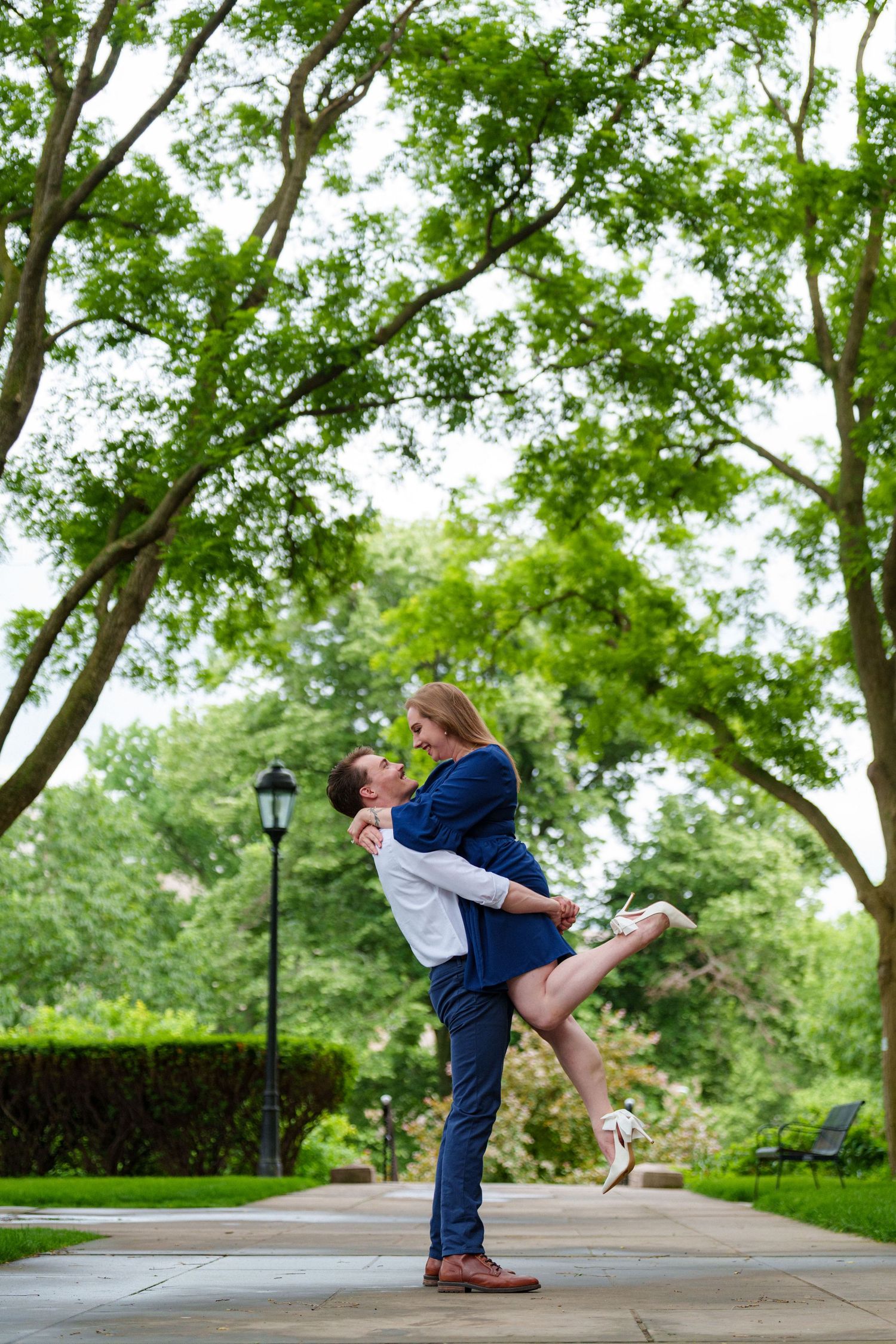 Joyful couple embracing in a lush green park, man lifting woman as they share a happy moment.