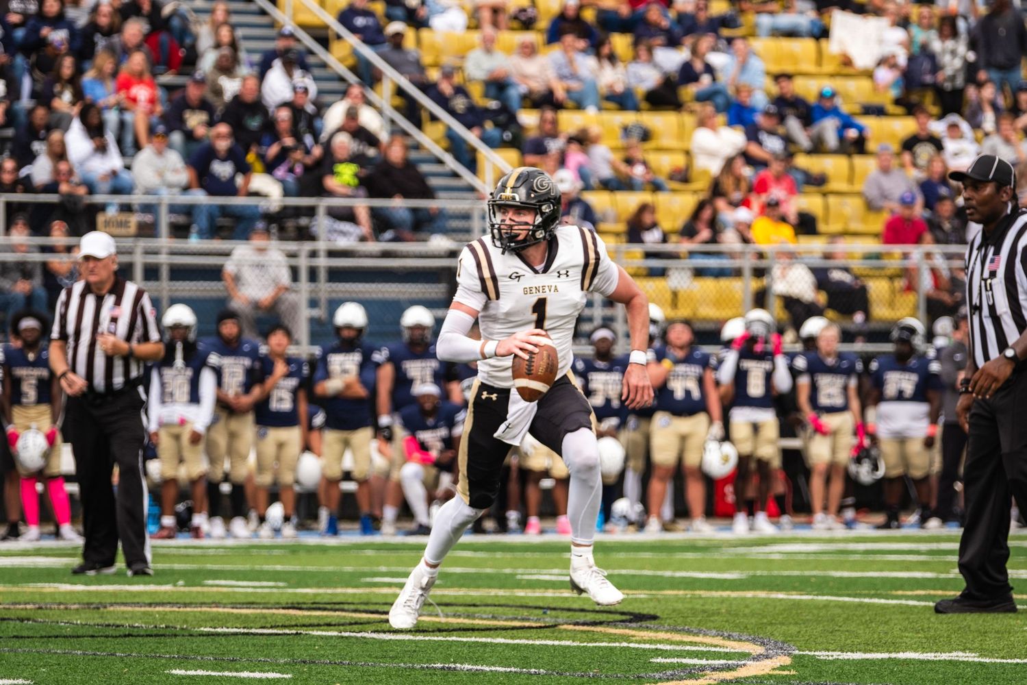 Football quarterback #1 in black uniform scrambles during college game.