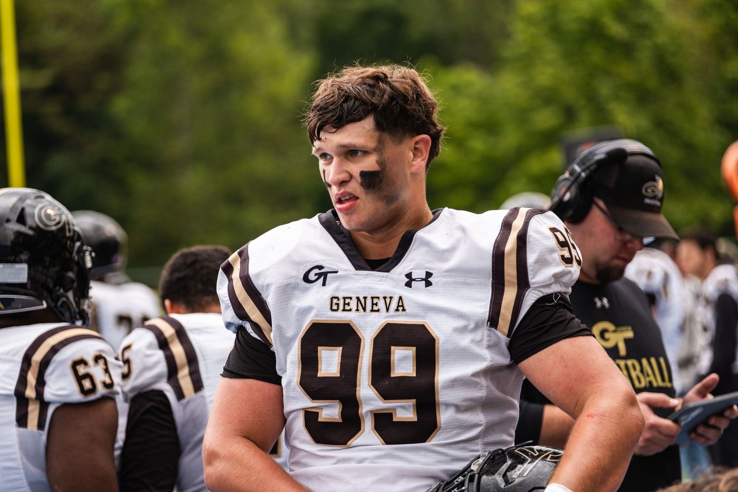 Geneva football player #99 stands on sideline during game.
