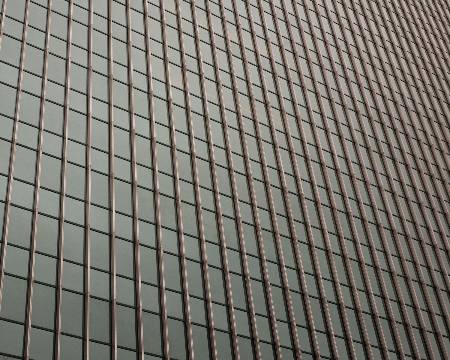 Looking up at modern glass skyscraper facade with geometric grid pattern of windows.