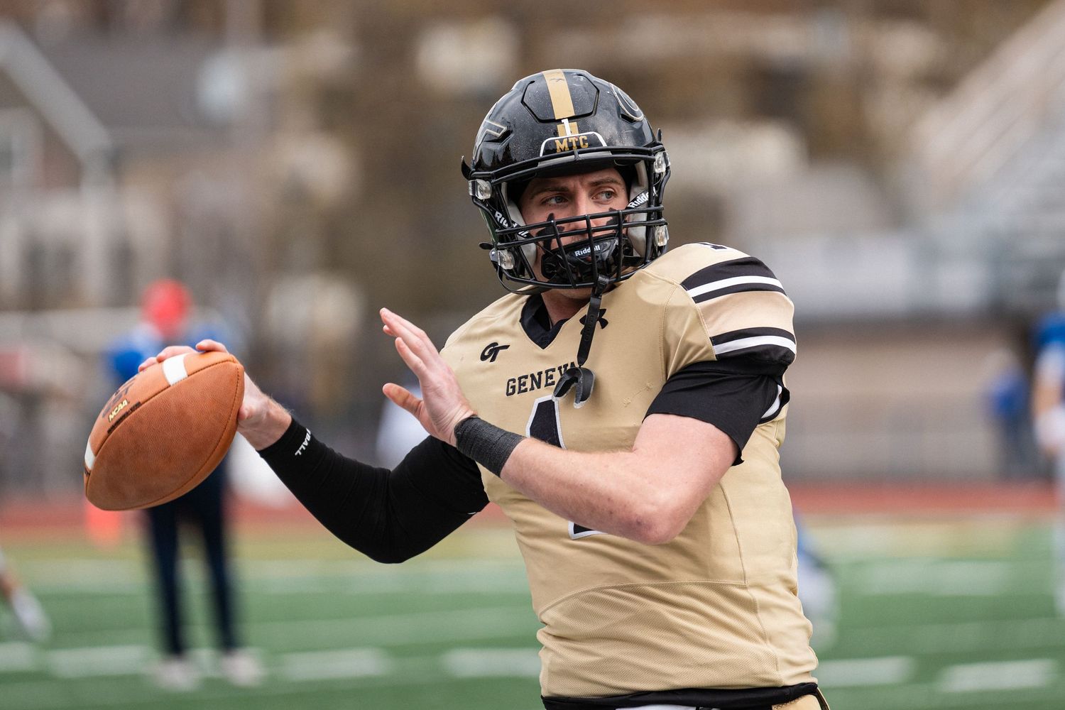 Geneva College football player in black and gold uniform prepares to catch a pass during a game.