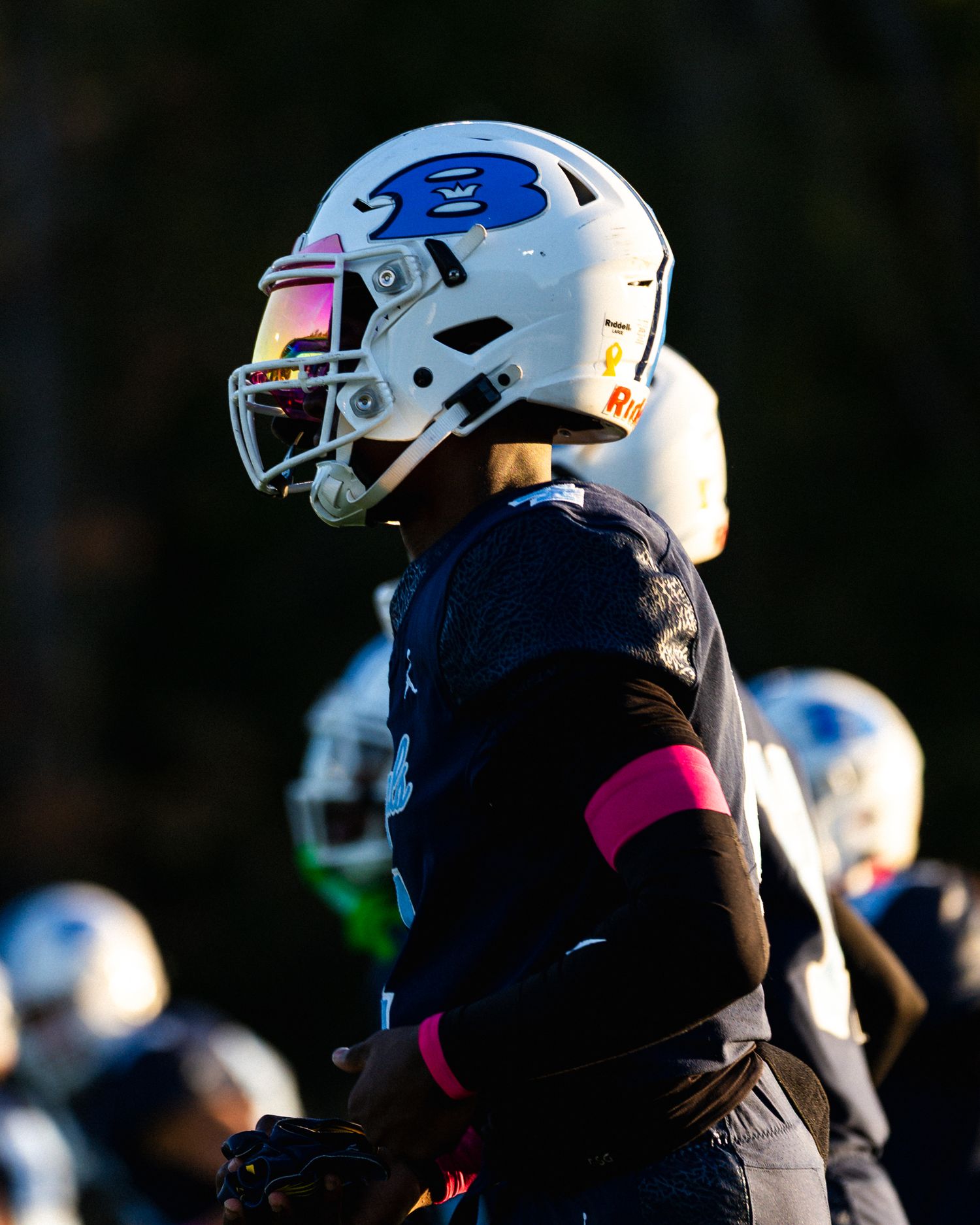 Close-up profile of Bengals football player in white helmet with pink visor in bright sunlight.
