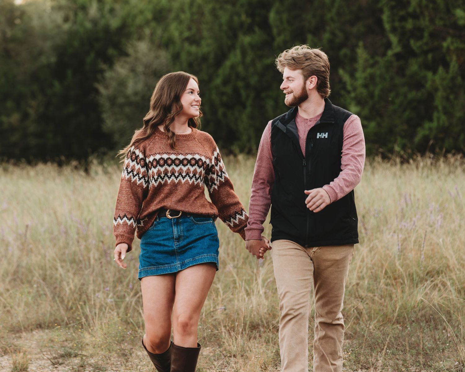 Couple walking hand in hand through golden field engagement session Waco TX Sudden Joy Visuals