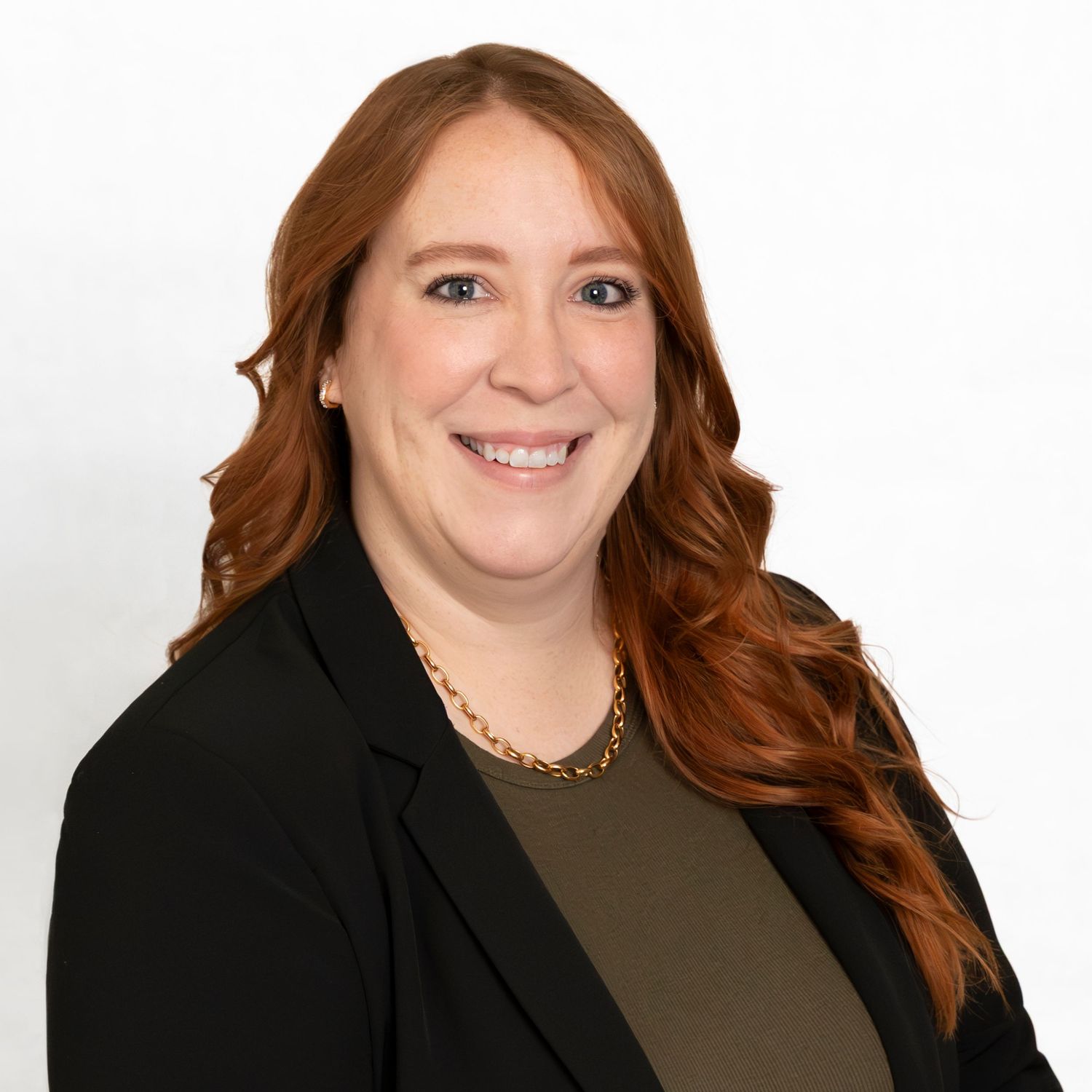 Professional headshot of person in black blazer and olive top against white background.