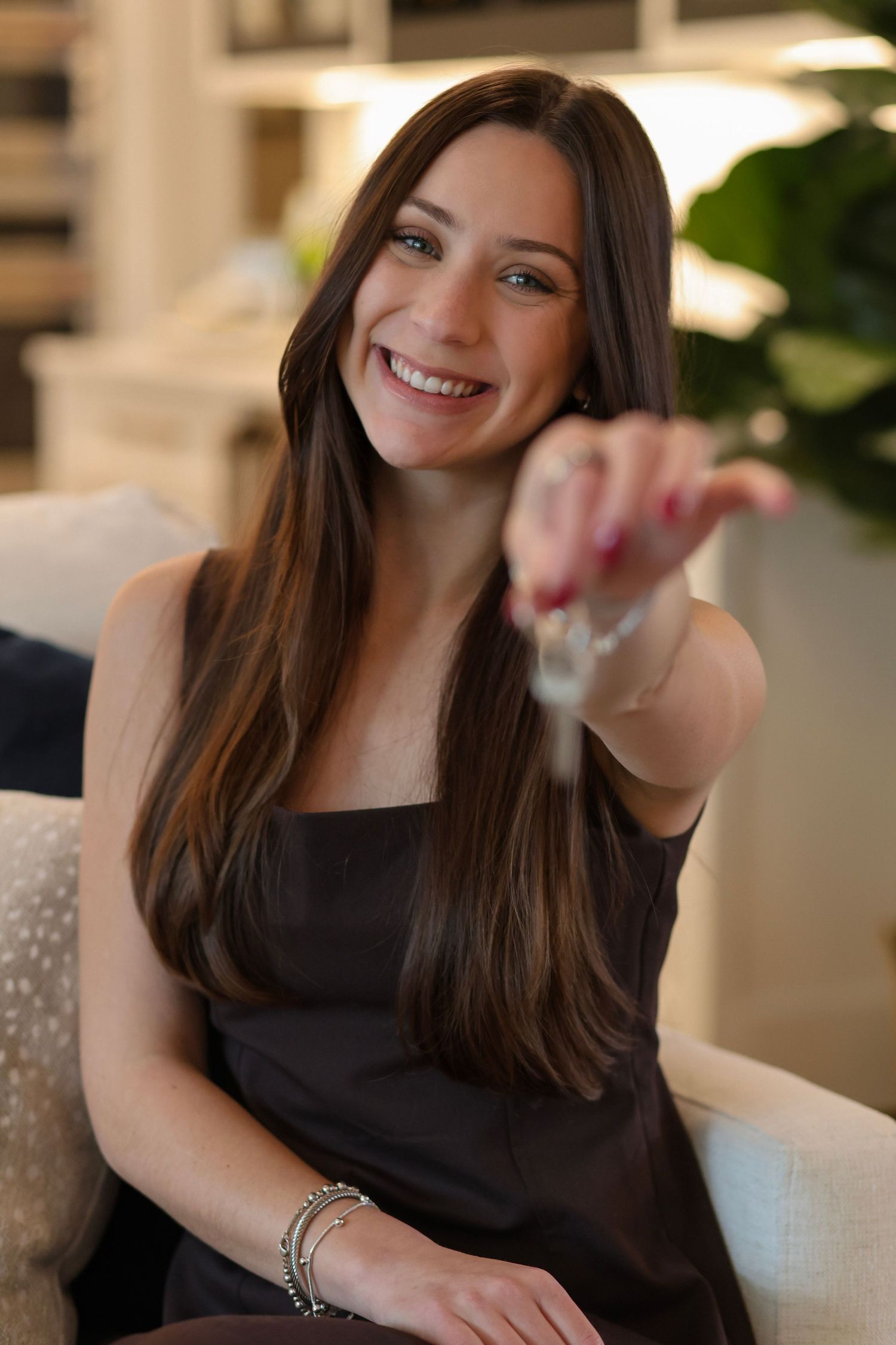 Professional lifestyle portrait of someone in a black top smiling warmly in an elegant indoor setting.