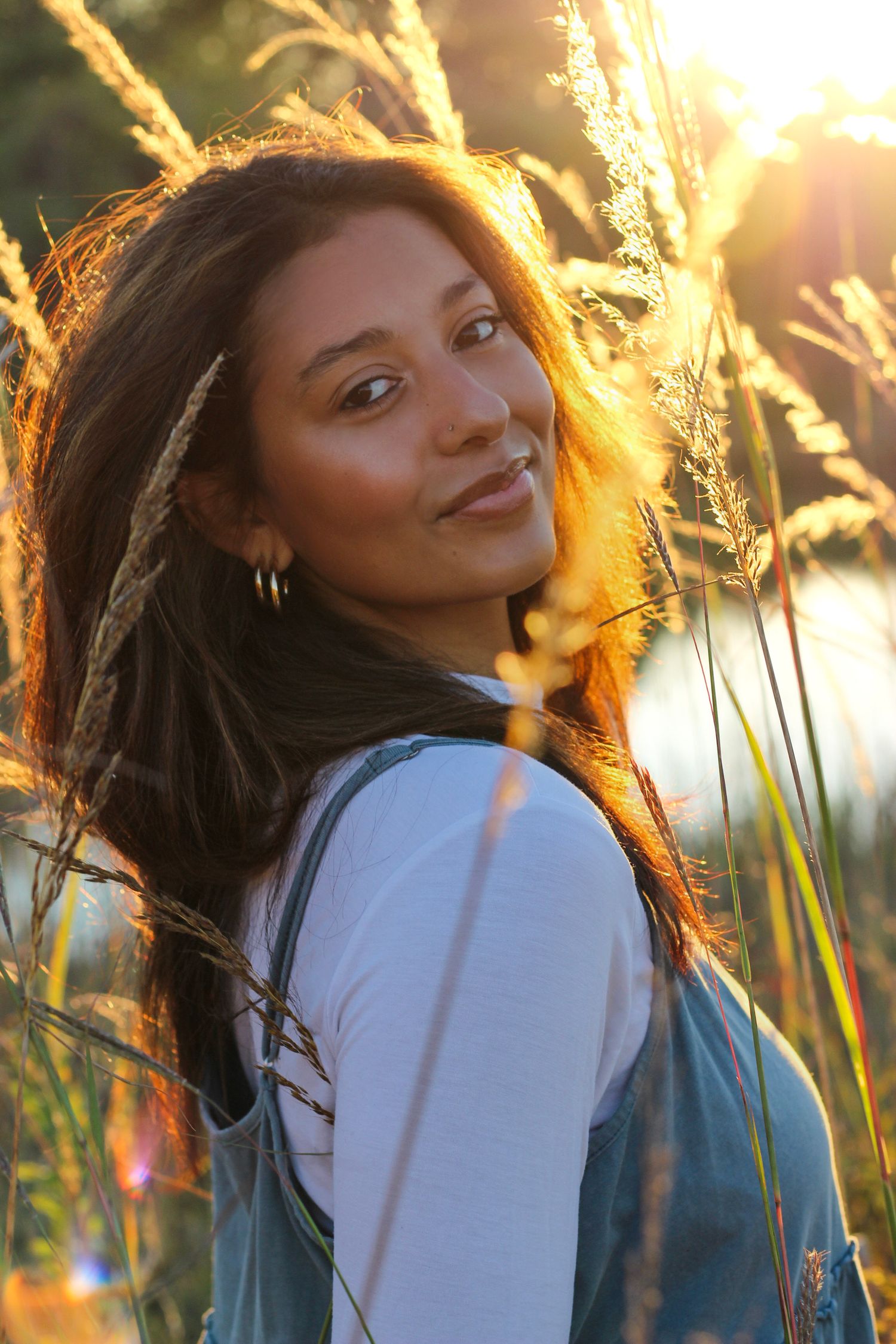 Artistic outdoor portrait with sunlit grass and natural backlighting creating a warm summer mood.