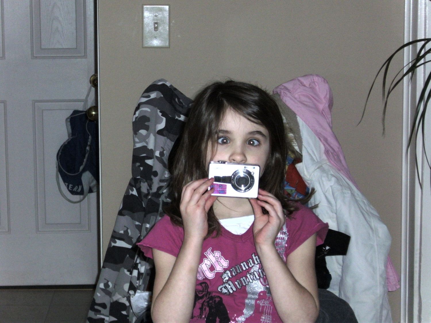 Young photographer holding a compact camera in an indoor setting.