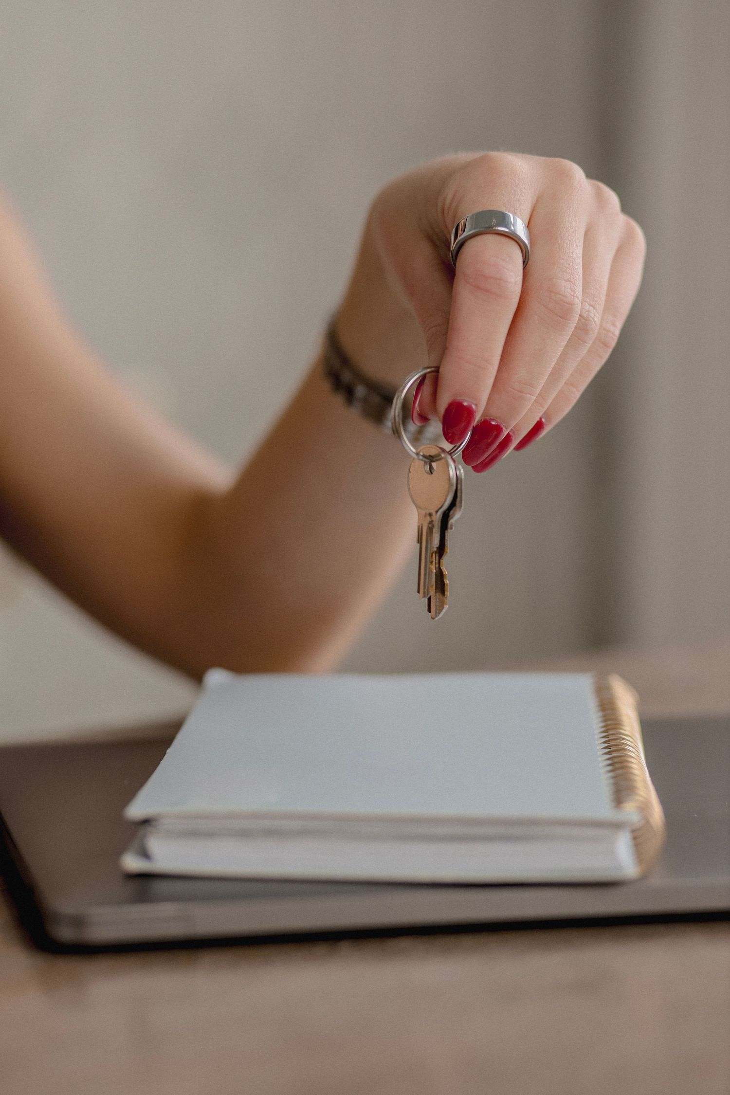 A sequence of hands holding keys flipping through pages of a white notebook on a wooden desk.