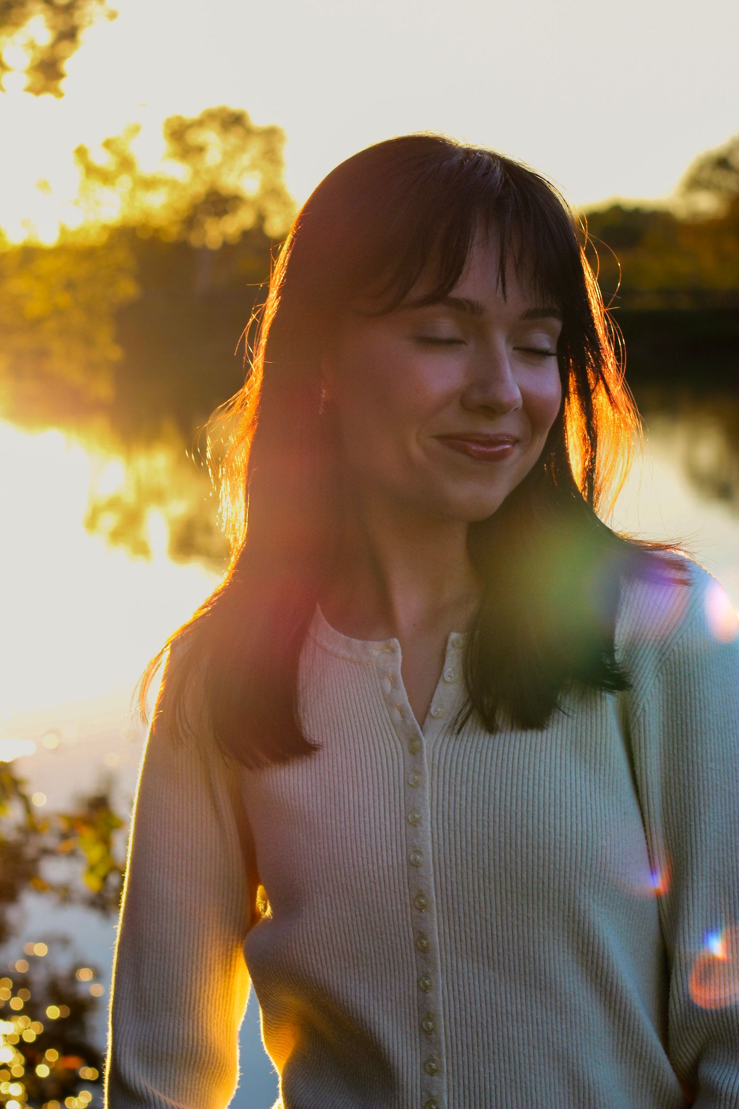 Sunset portrait with golden backlight and water reflection in background.
