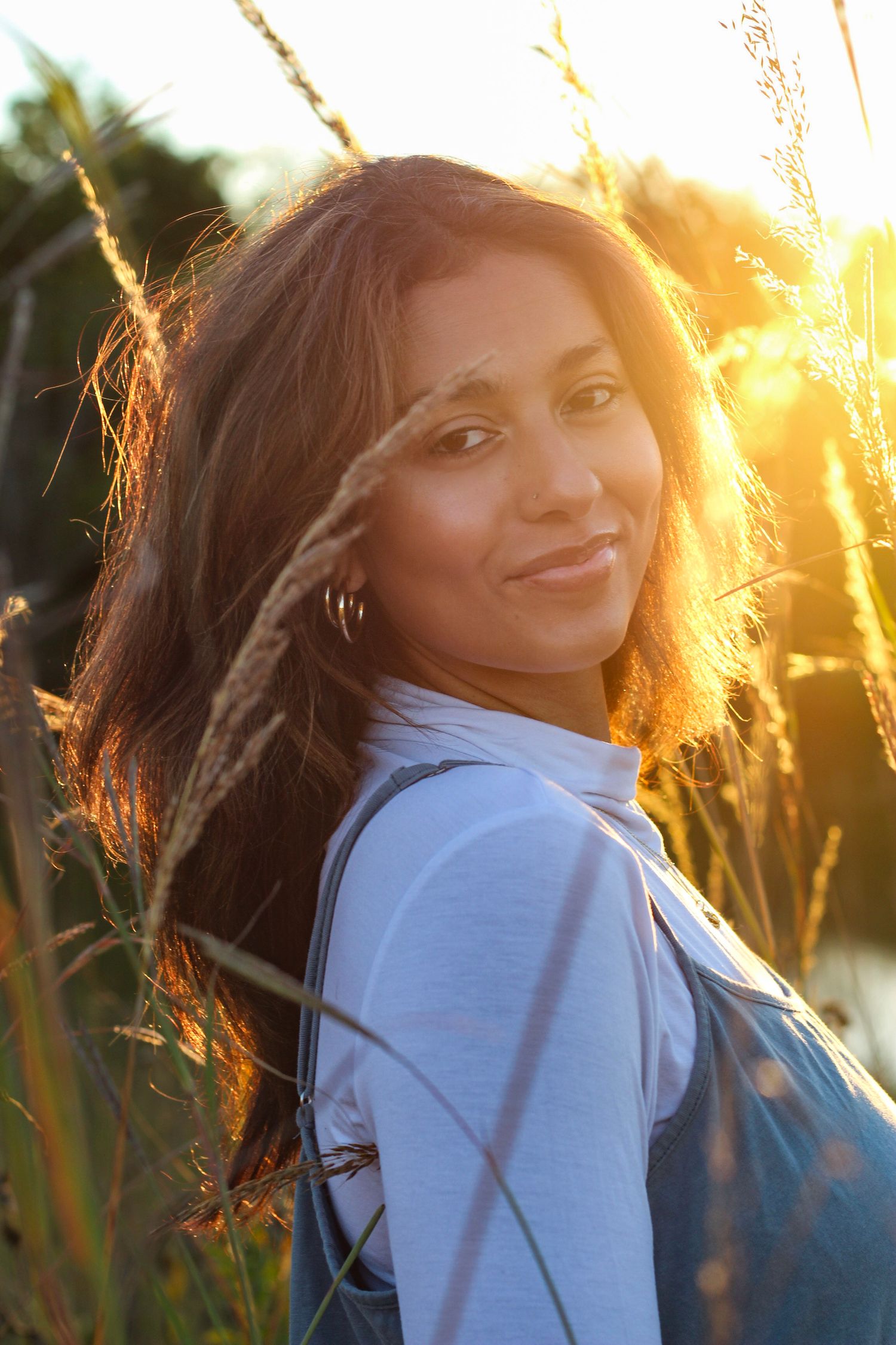 Joyful outdoor portrait with sunlit hair and natural backlighting at sunset.